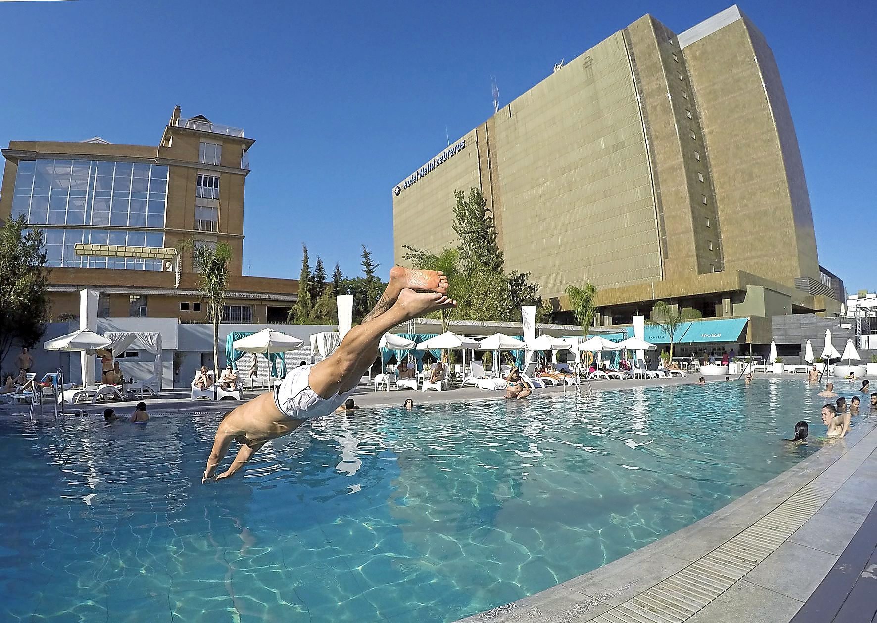 Un usuario se zambulle en la piscina de un hotel en Sevilla.