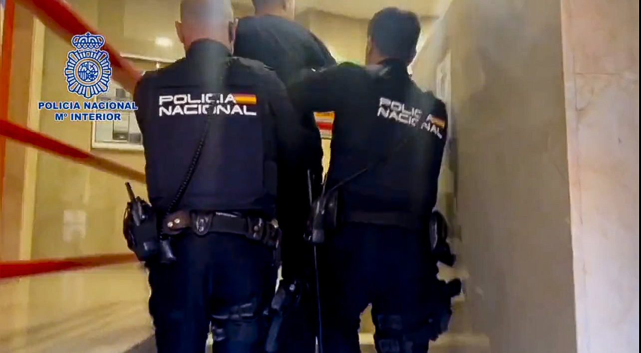 Dos agentes de la Polica Nacional trasladan a un detenido en Murcia.