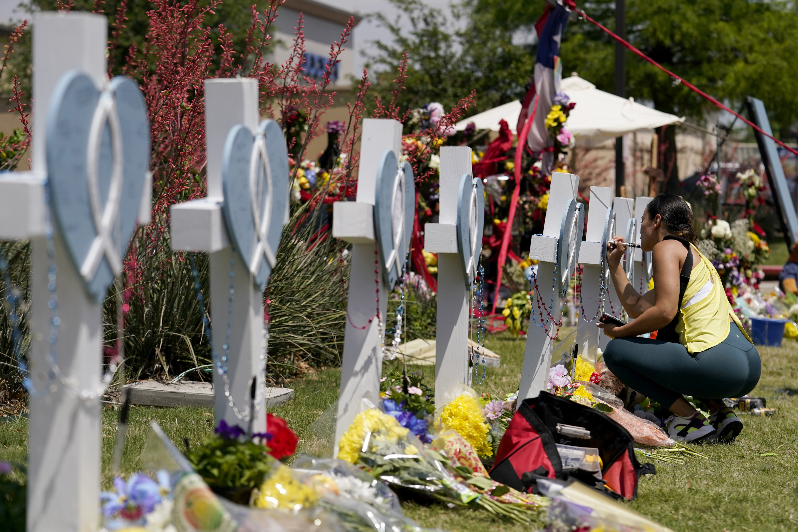 Una mujer firma una cruz alineada junto a otras en un altar improvisado en honor de las vctimas de una masacre, el lunes 8 de mayo de 2023, en Allen Texas.