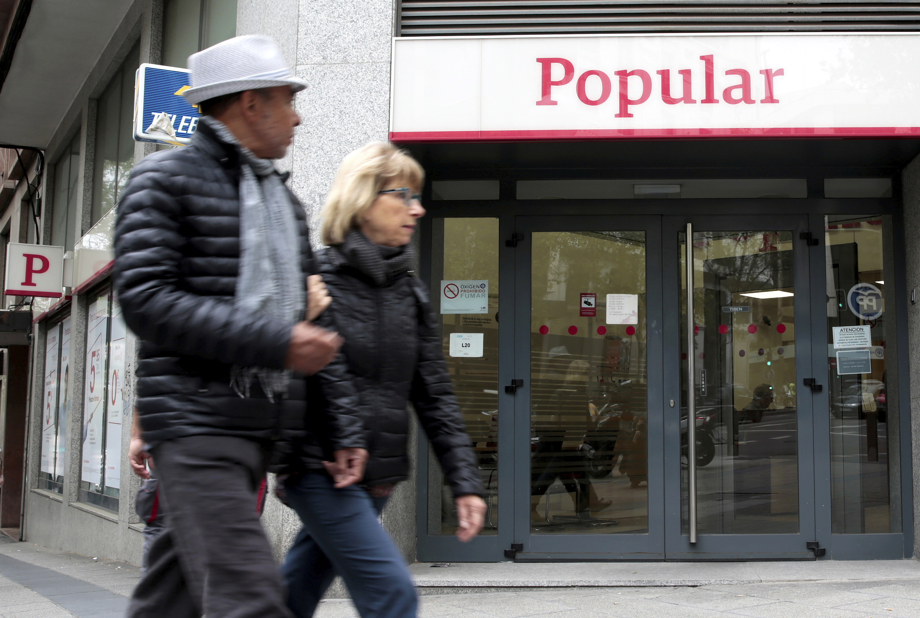 Dos personas pasan por delante de una sucursal de Banco Popular en Madrid.