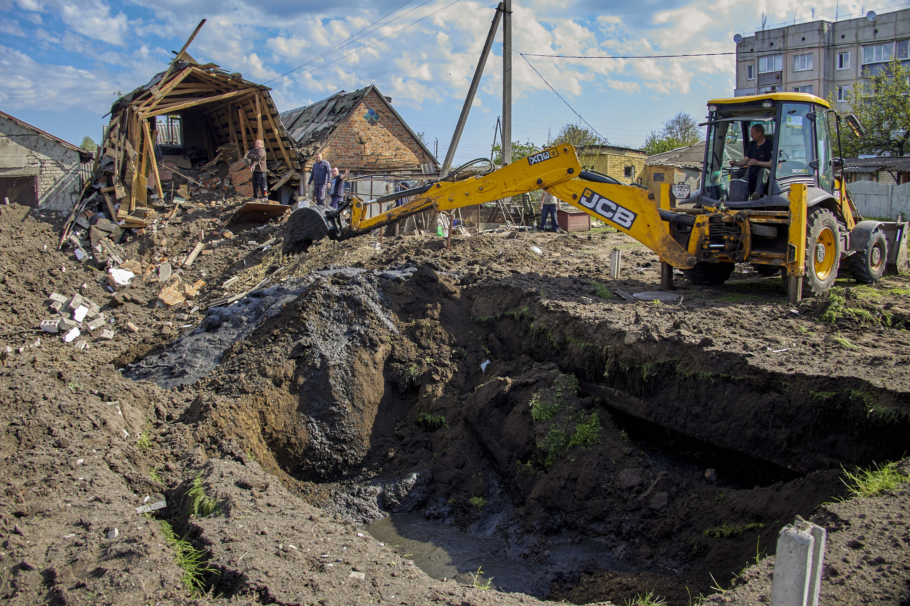 Locales limpian los escombros y reparan las tuberas daadas despus de un ataque con cohetes en el asentamiento de Zolochiv.