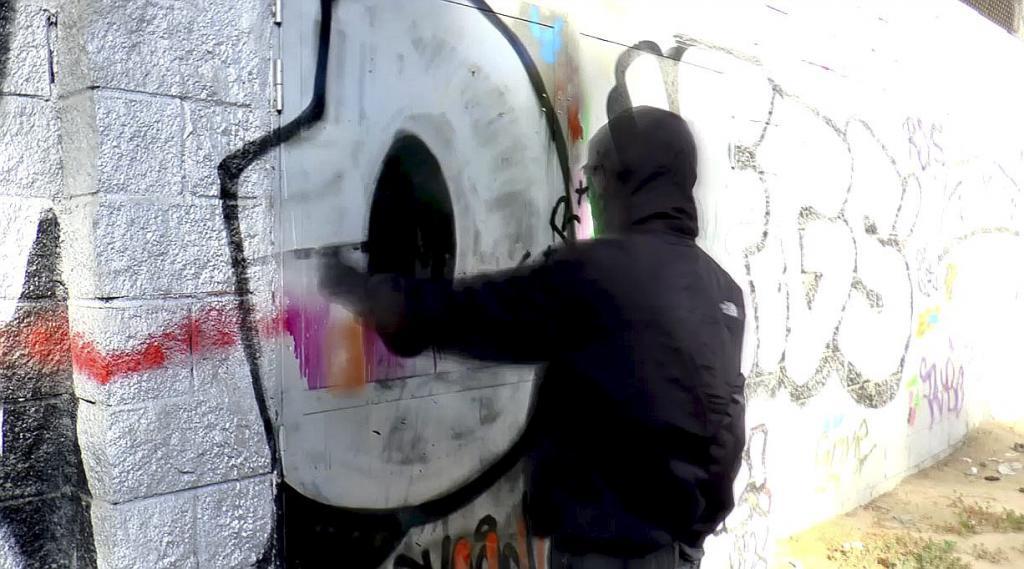 Una persona pintando un grafiti en una pared.