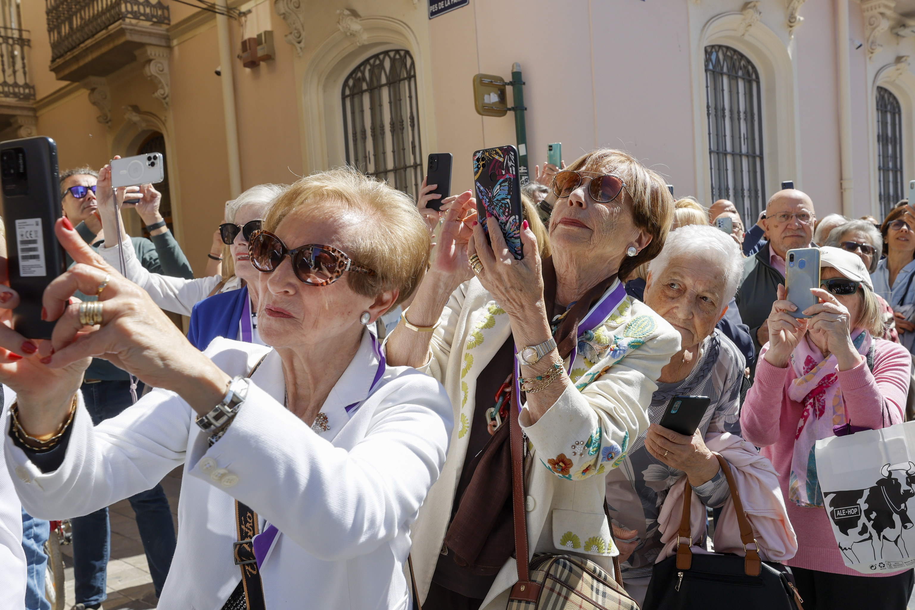 Varias personas con su teléfono al paso de una procesión en Valencia