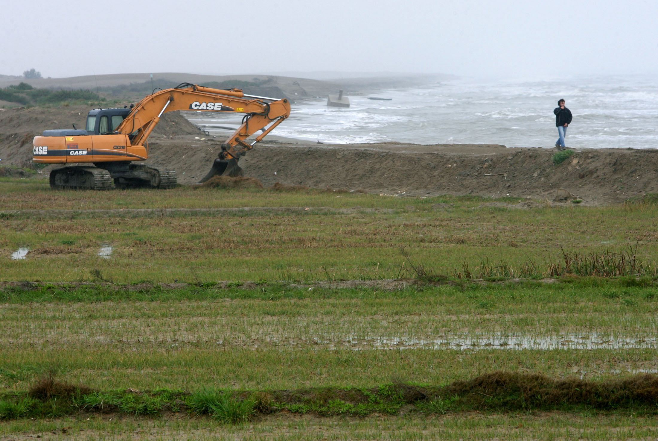 Una excavadora refuerza los muros de contencin para prevenir la inundacin junto al mar en el Delta del Ebro.
