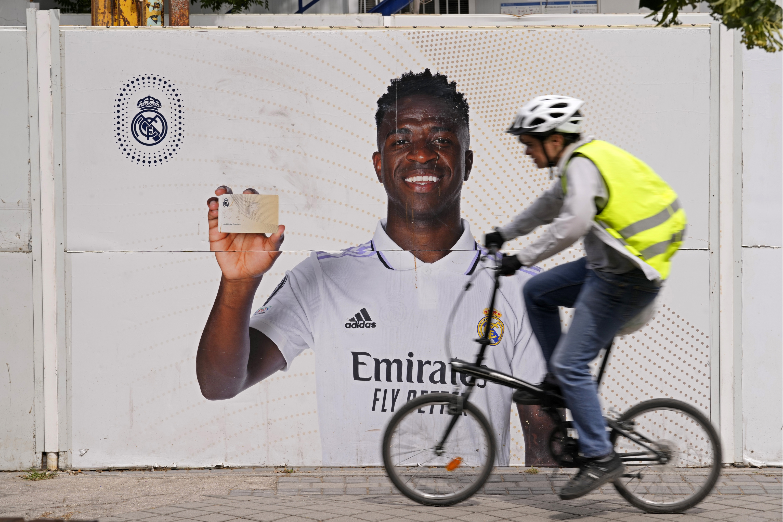 Un ciclista pasa este lunes frente a un anuncio con la imagen de Vinicius, frente al estadio Santiago Bernábeu.
