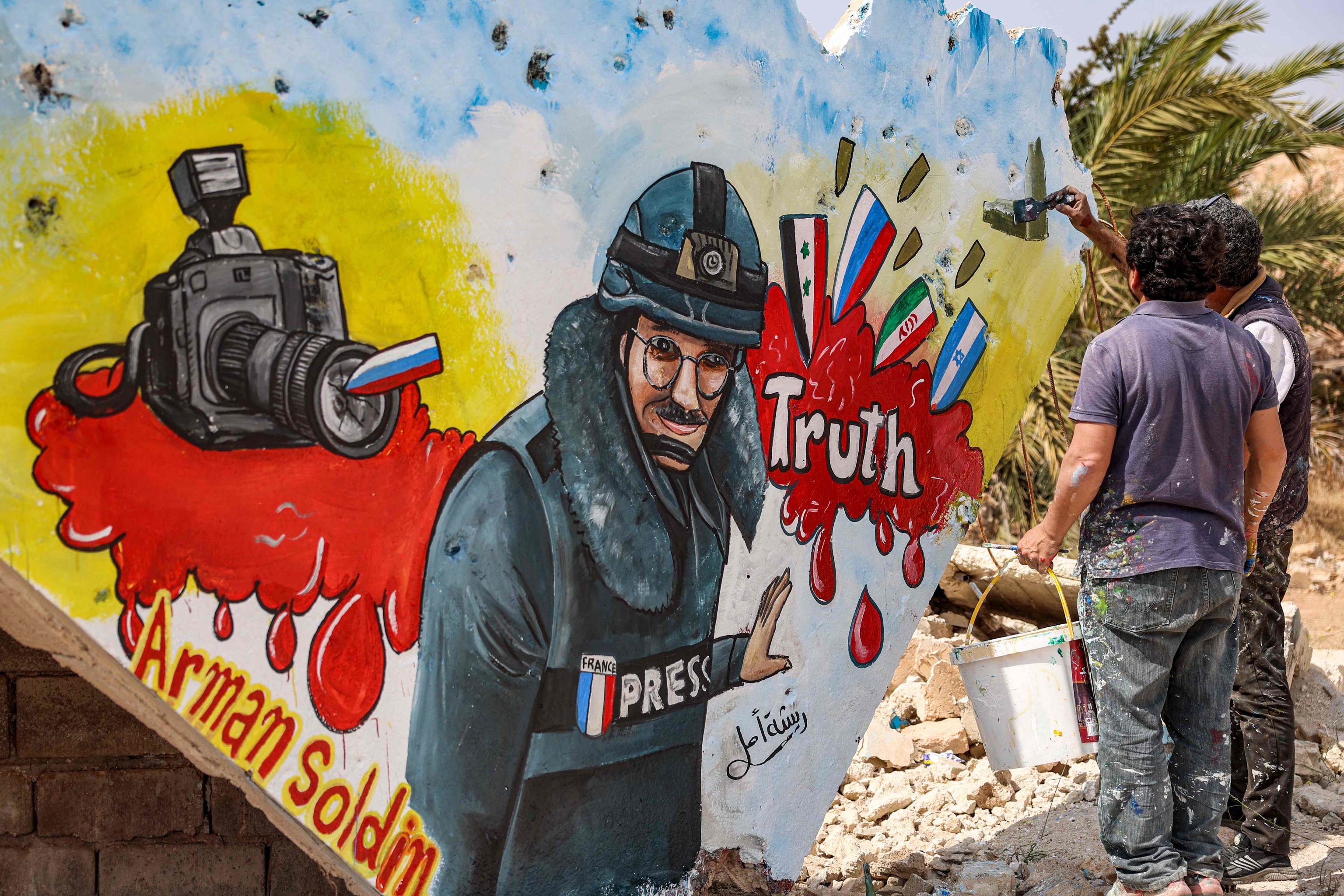 Artistas sirios dibujan en un mural al periodista Arman Soldin muerto en Ucrania.