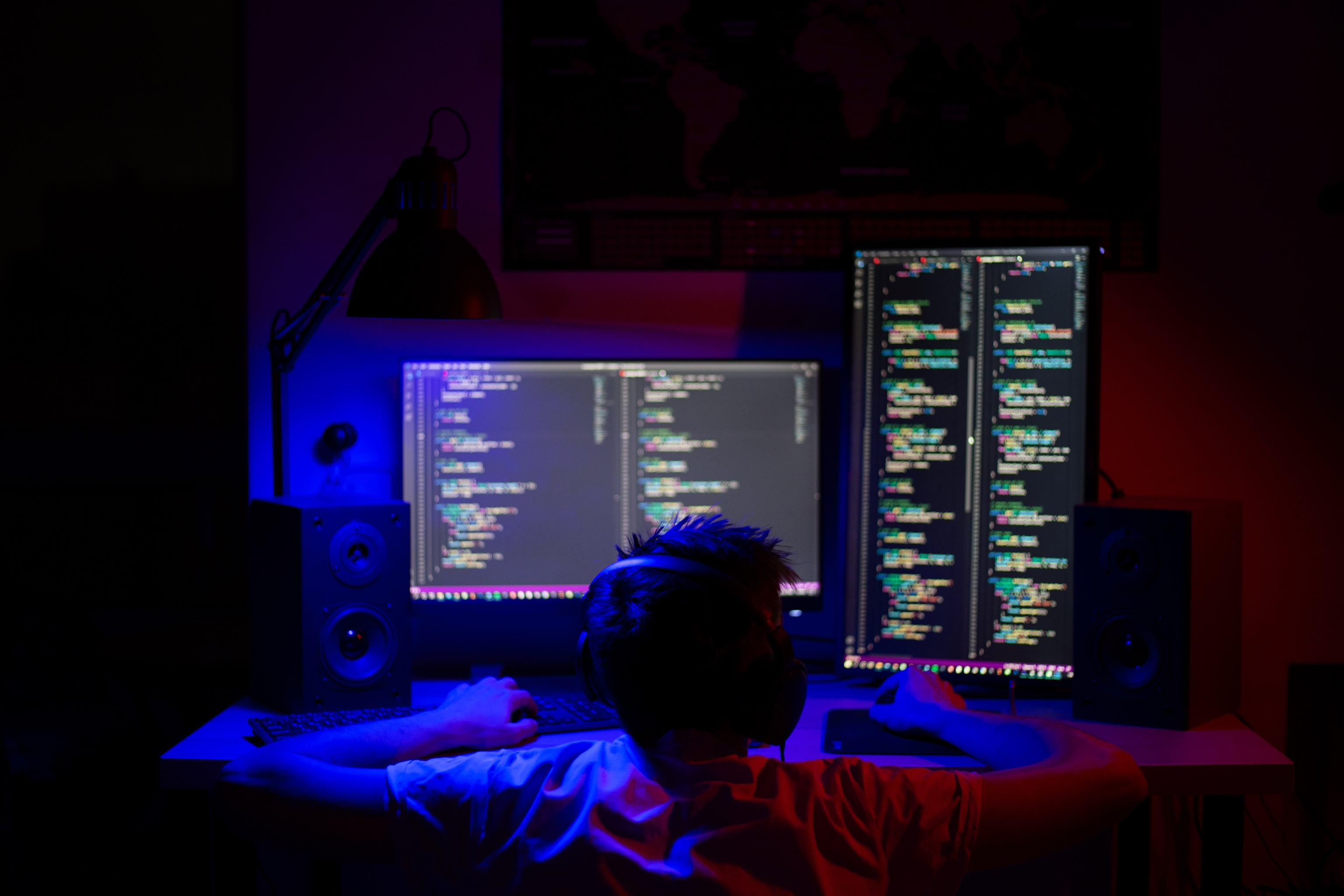 Imagen de un joven programador escribiendo código ante sus pantallas.
