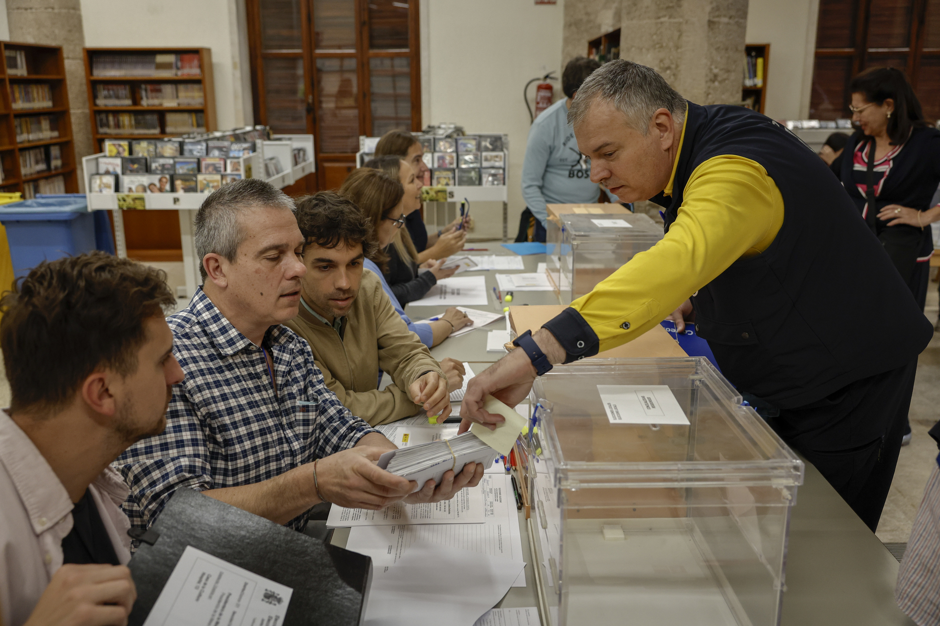 Un cartero entrega los votos emitidos por correo en una mesa electoral
