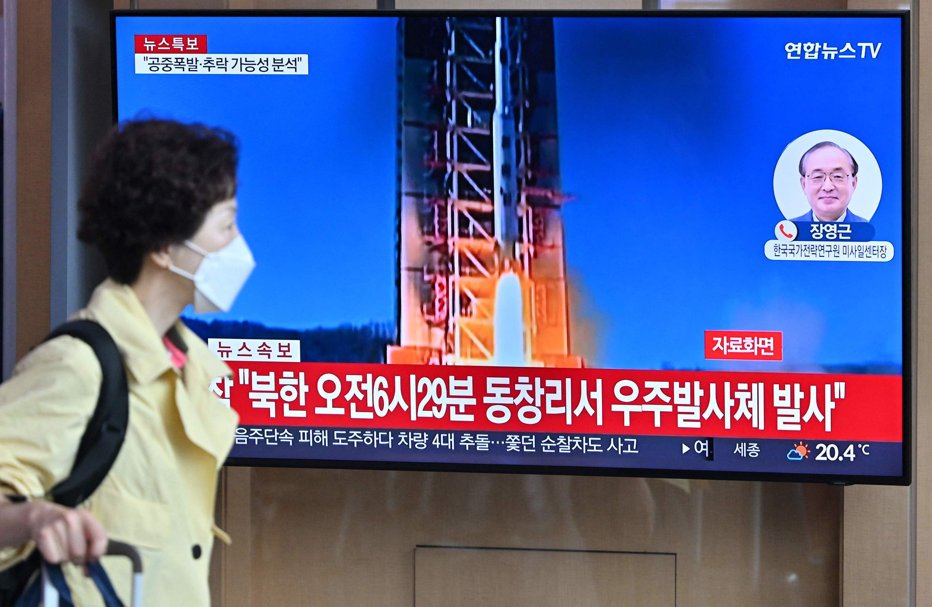 Una mujer camina en un estación de Seúl junto a una pantalla que emite el lanzamiento.