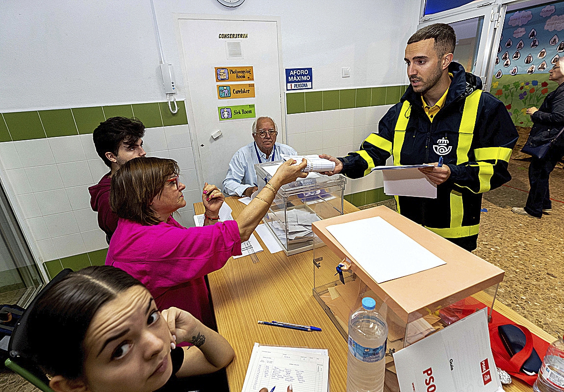 Un cartero entrega el voto por correo en una mesa electoral el pasado 28-M.