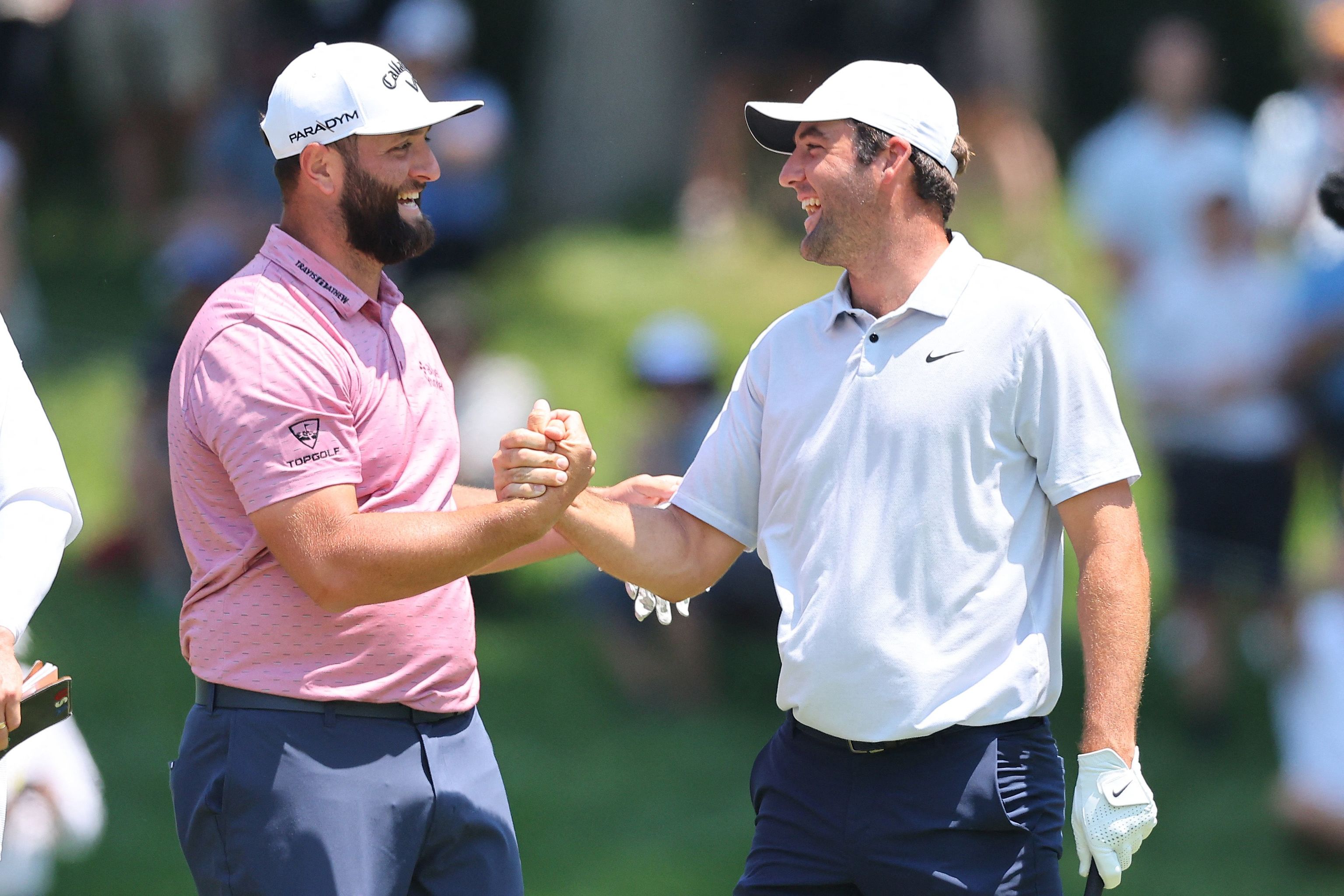 Jon Rahm choca la mano con Scottie Scheffler.