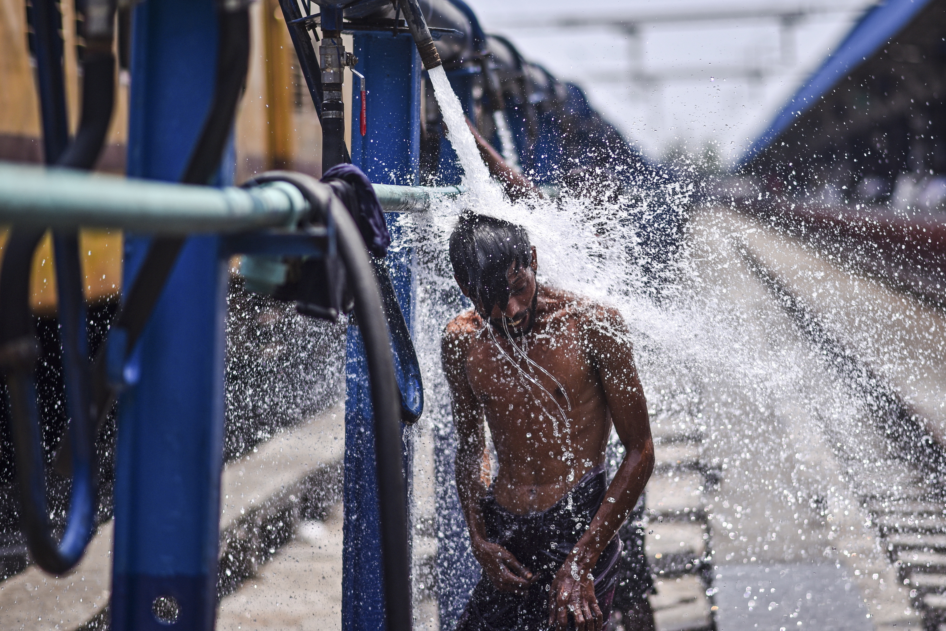 Un pasajero se refresca con el agua de una tubera en la Estacin Central de Trenes de Chennai.