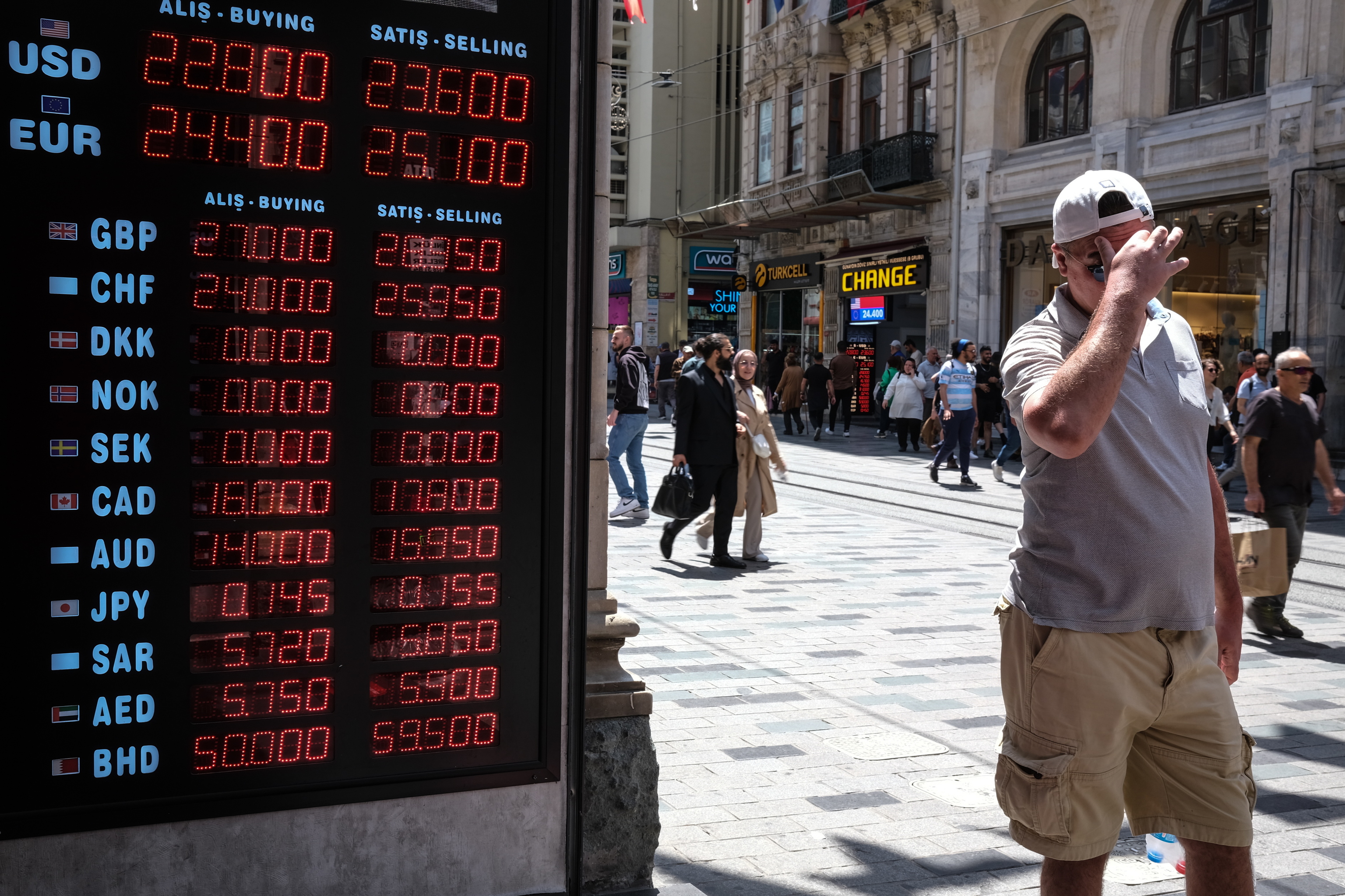 Un hombre camina cerca de una pizarra de cambio de divisas en Estambul