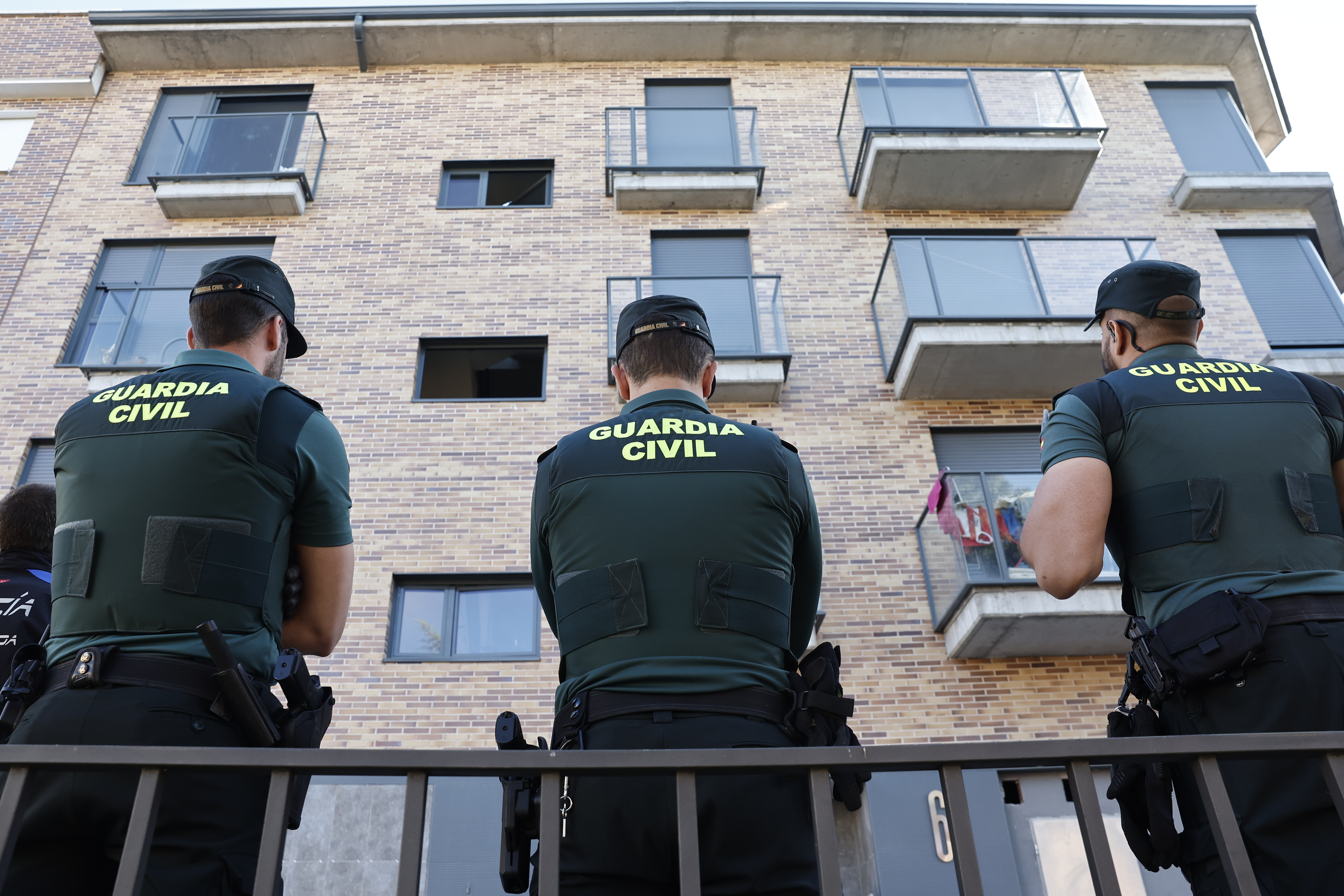 Dos efectivos de la Guardia Civil delante de un bloque de pisos.