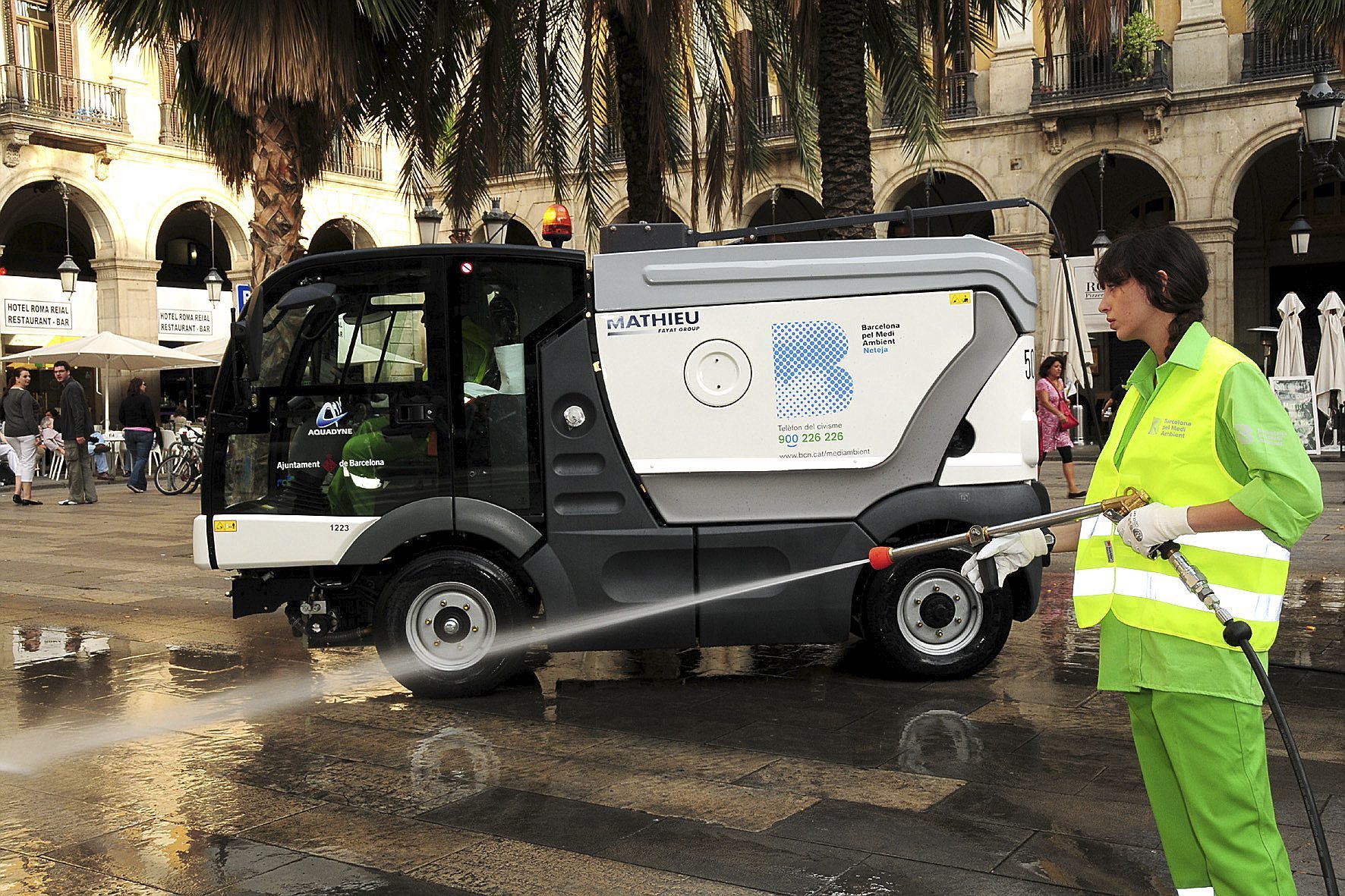 Personal de los servicios de limpieza de Barcelona limpiando con agua una calle.