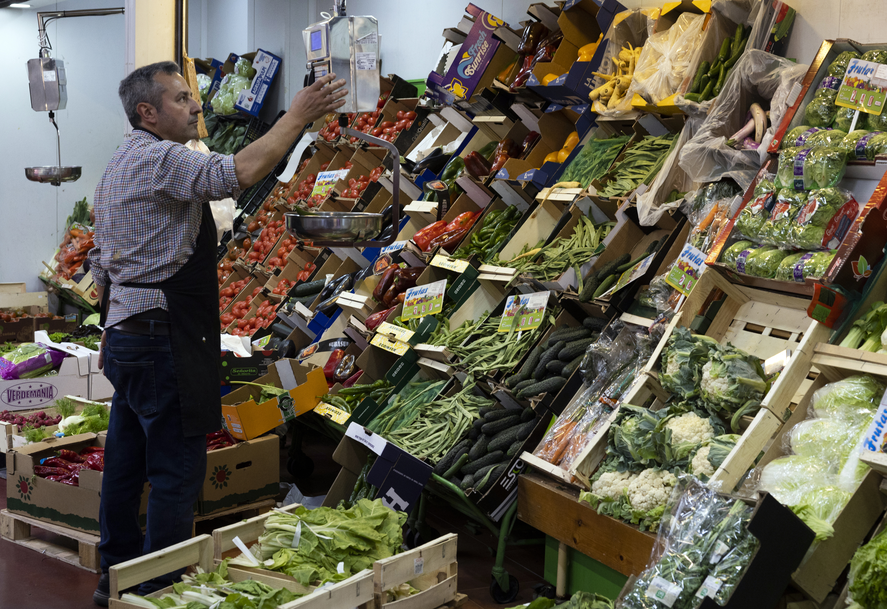 Un hombre trabaja en una parada de frutas y verduras del Mercado de la Cebada de Madrid.