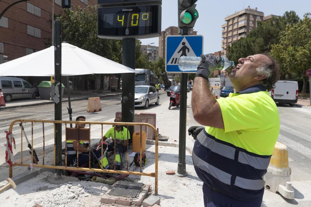 Un trabajador bebe agua junto a un termómetro que marca 40 grados en Murcia.