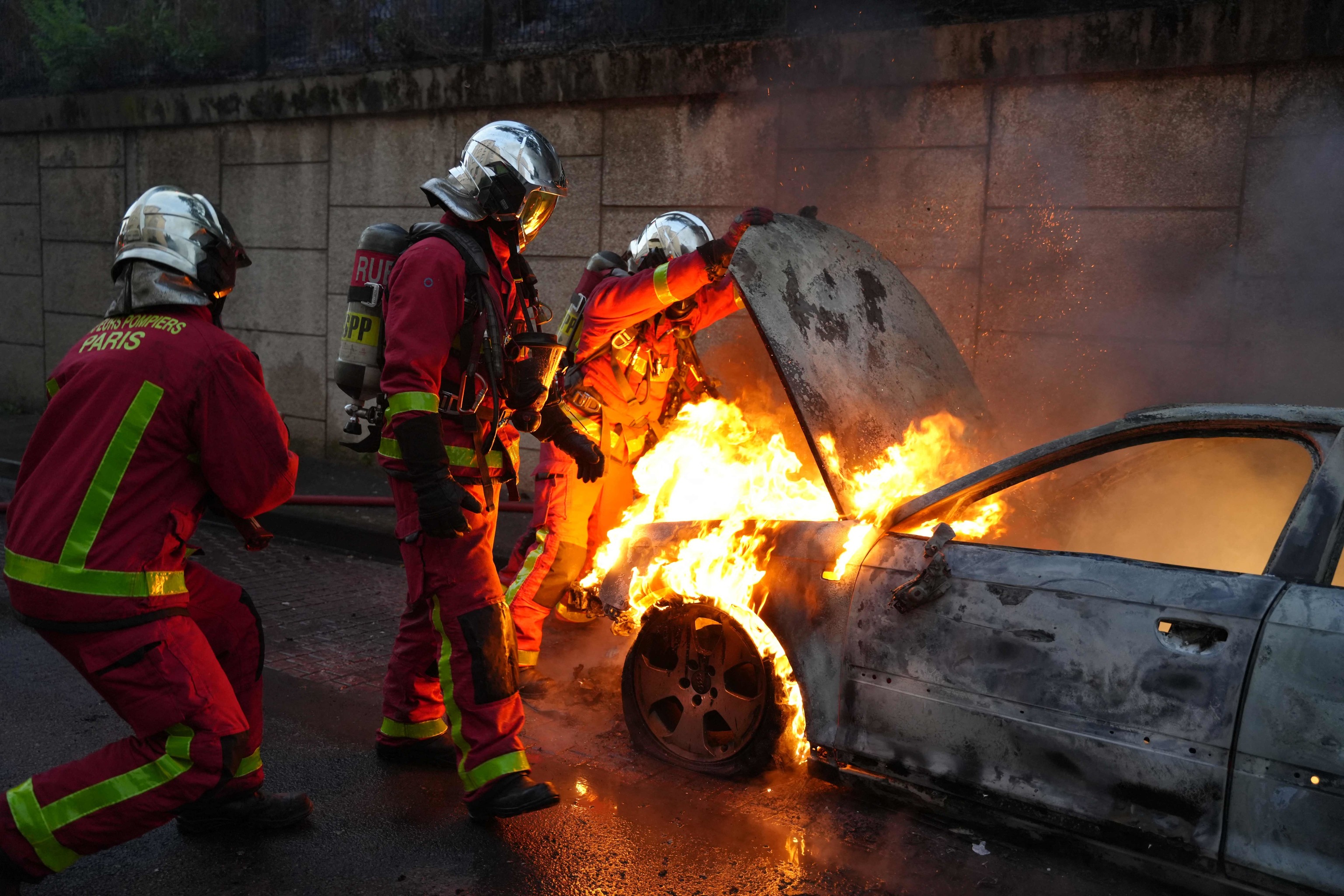 Bomberos intentan apagar el fuego en un coche incendiado en Nanterre