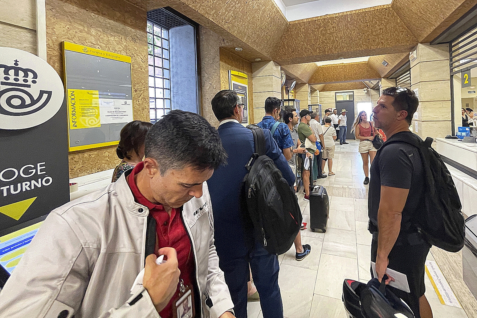 Varias personas hacen cola en una oficina de Correos para preguntar por el voto por correo, ayer en el centro de Madrid.