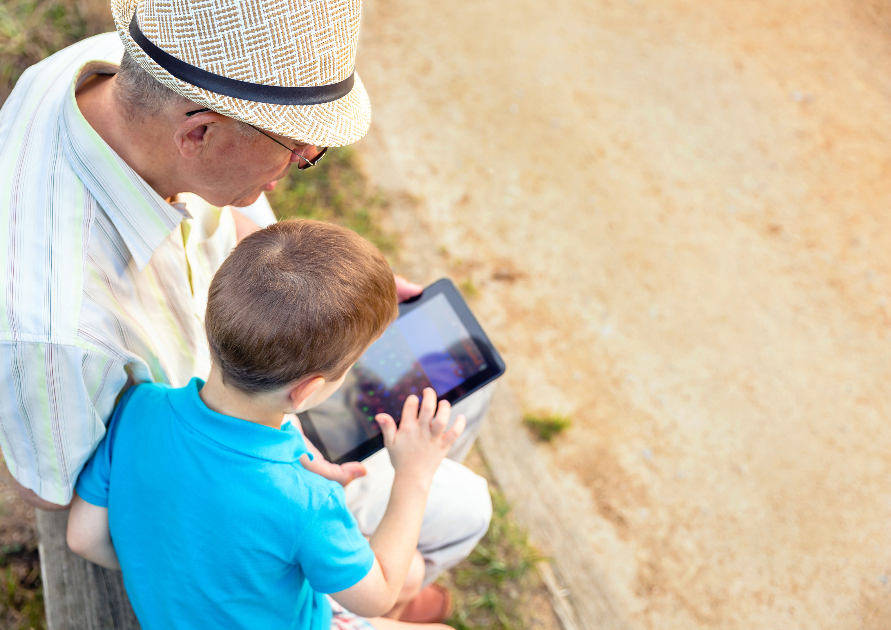 Un abuelo y su nieto mirando la pantalla de una tablet.