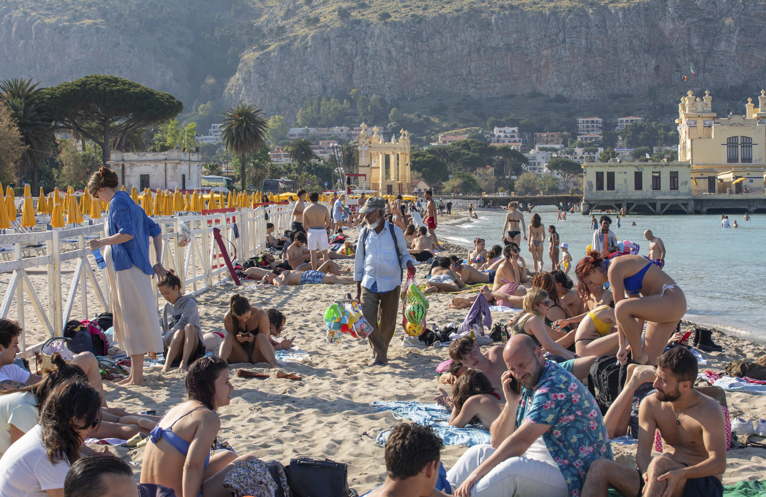 Un vendedor ambulante ofrece sus productos a los bañistas de la playa de Mondello (Palermo).
