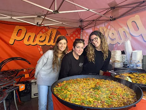 Esther Chinchilla, dueña del puesto de paellas en el mercado The Rocks de Sidney, con dos estudiantes españolas