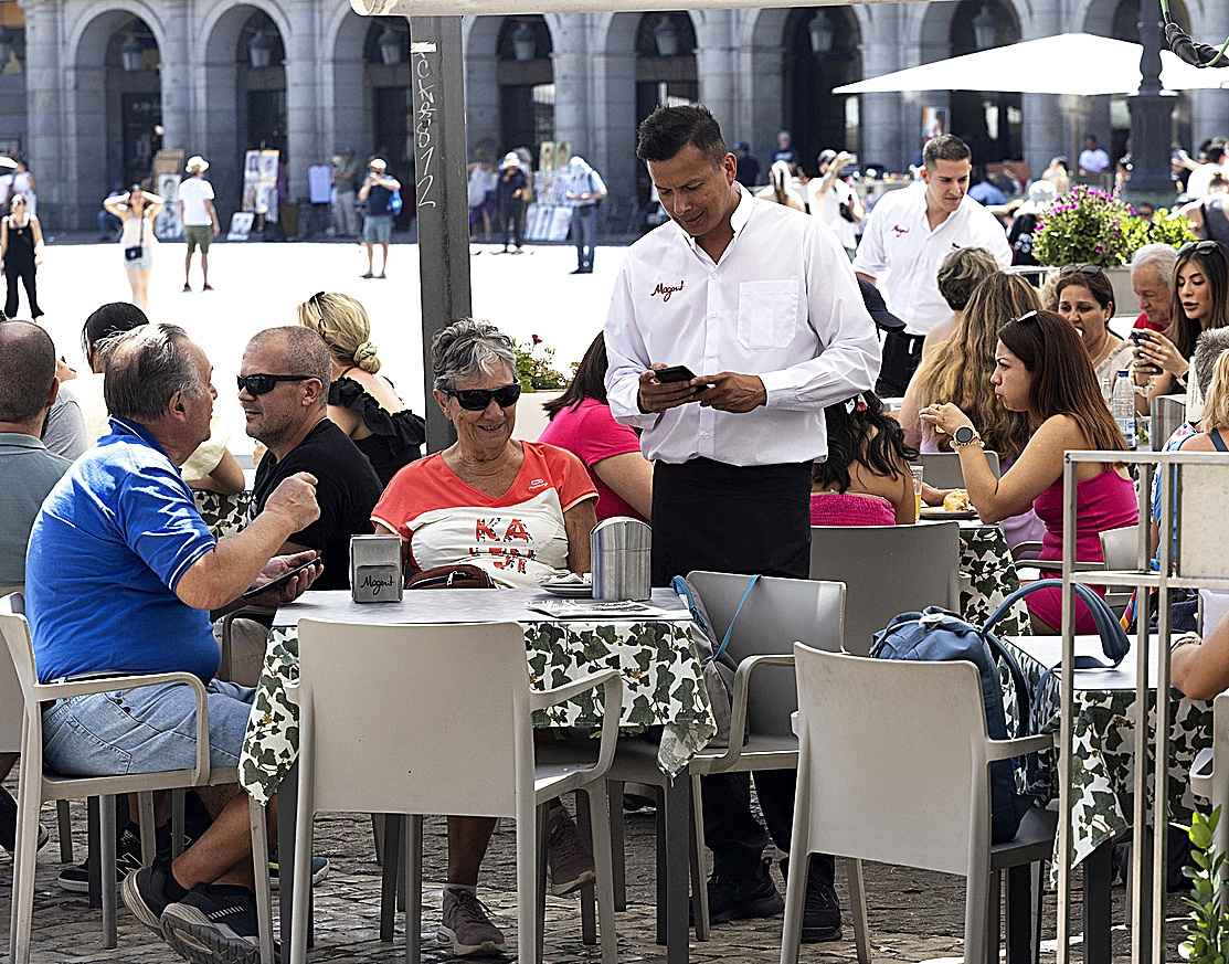 Un camarero atiende una mesa en plaza mayor, Madrid