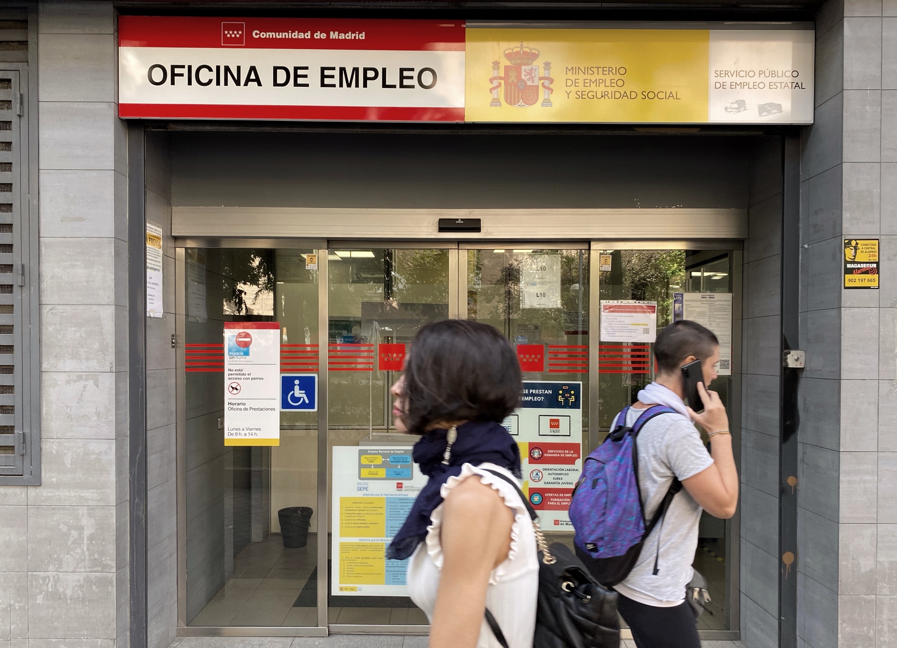 Dos personas pasan por la oficina de empleo de Acacias, Madrid.