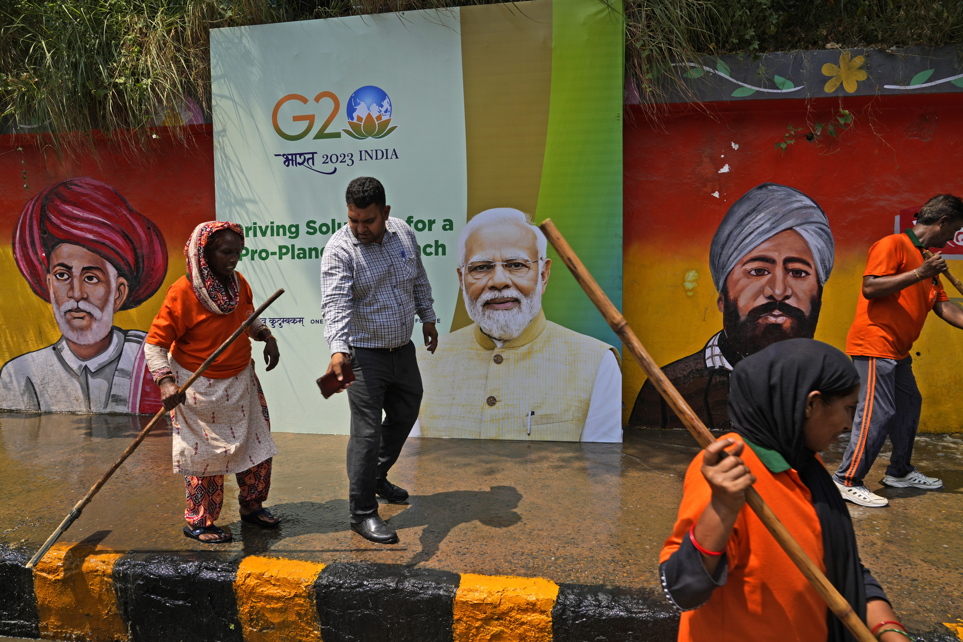 Trabajadores municipales juntos a una valla publicitaria representando a Narendra Modi.