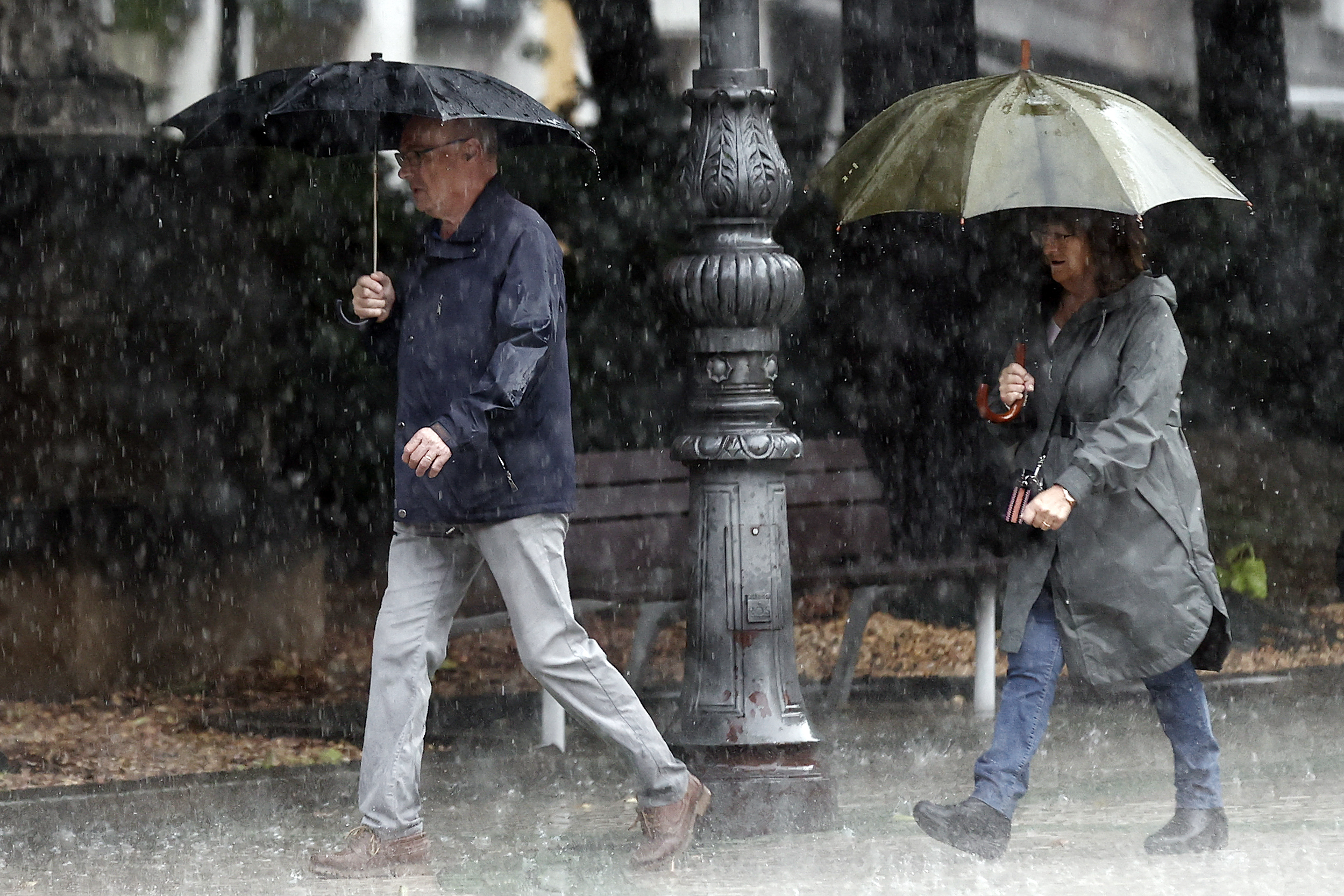Dos personas se protegen de la lluvia con sus paraguas en Pamplona.