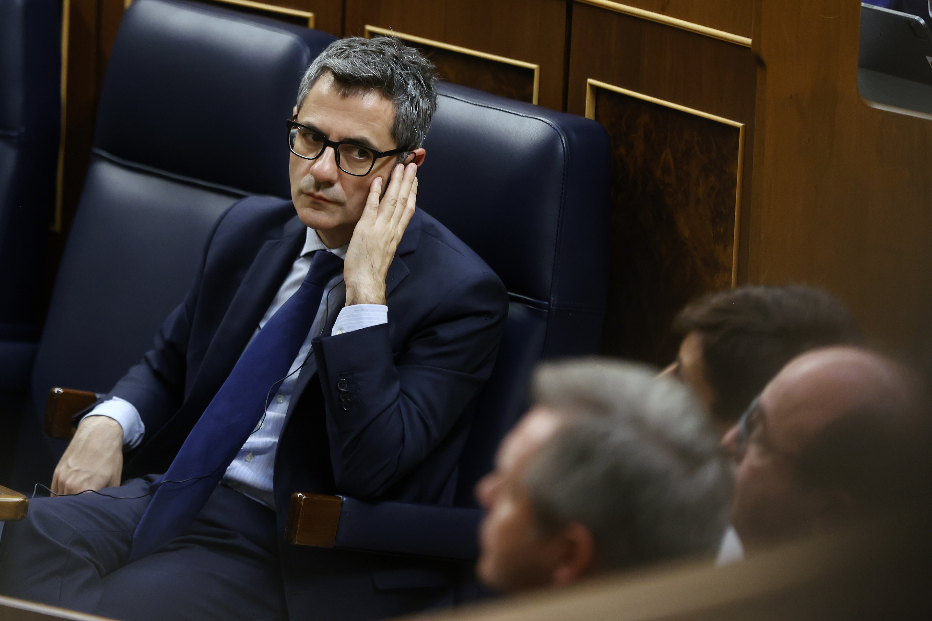 Félix Bolaños escucha con un auricular una intervención en el Congreso.