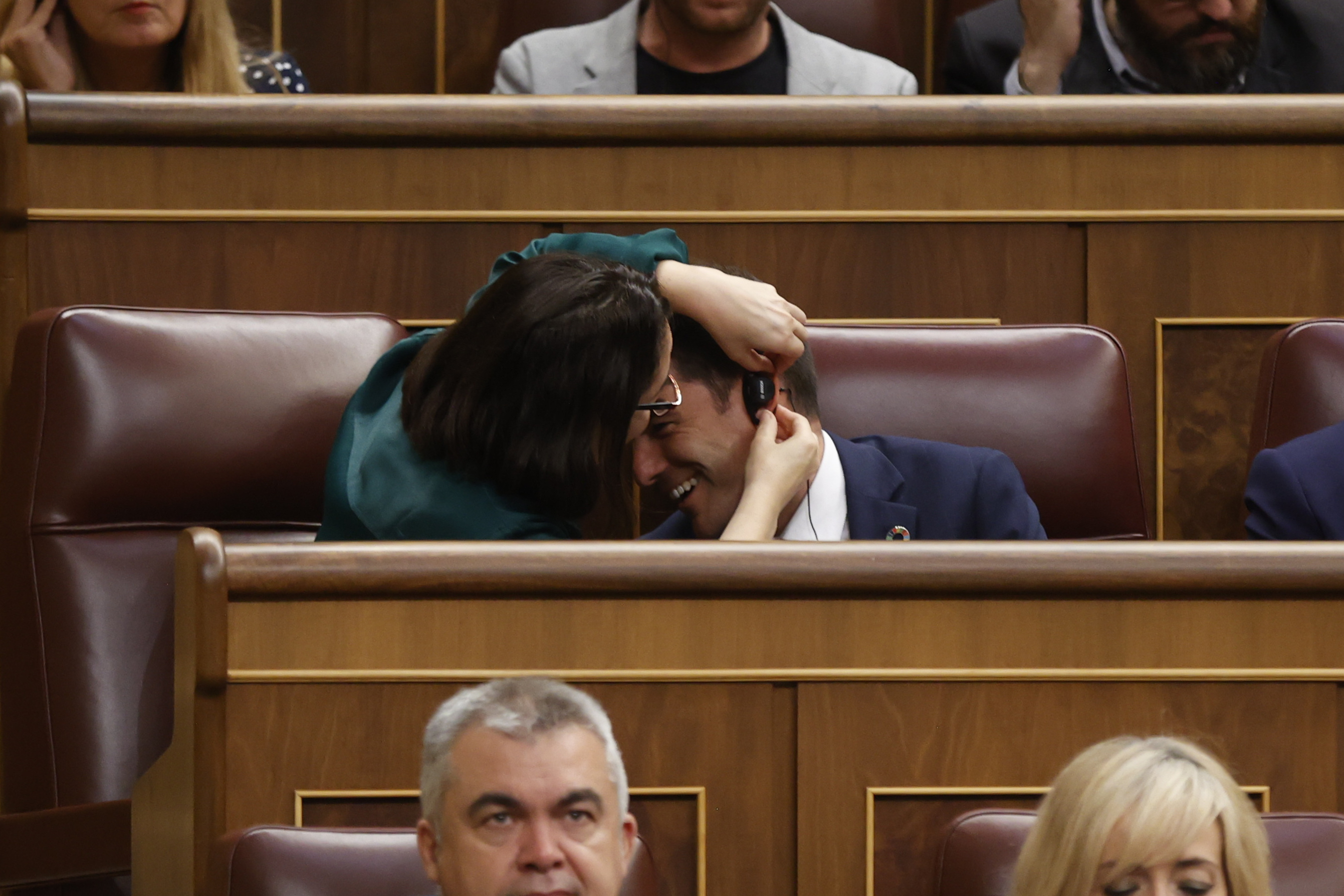 Bir milletvekili, bir meslektaşının kulaklığı takmasına yardım ediyor