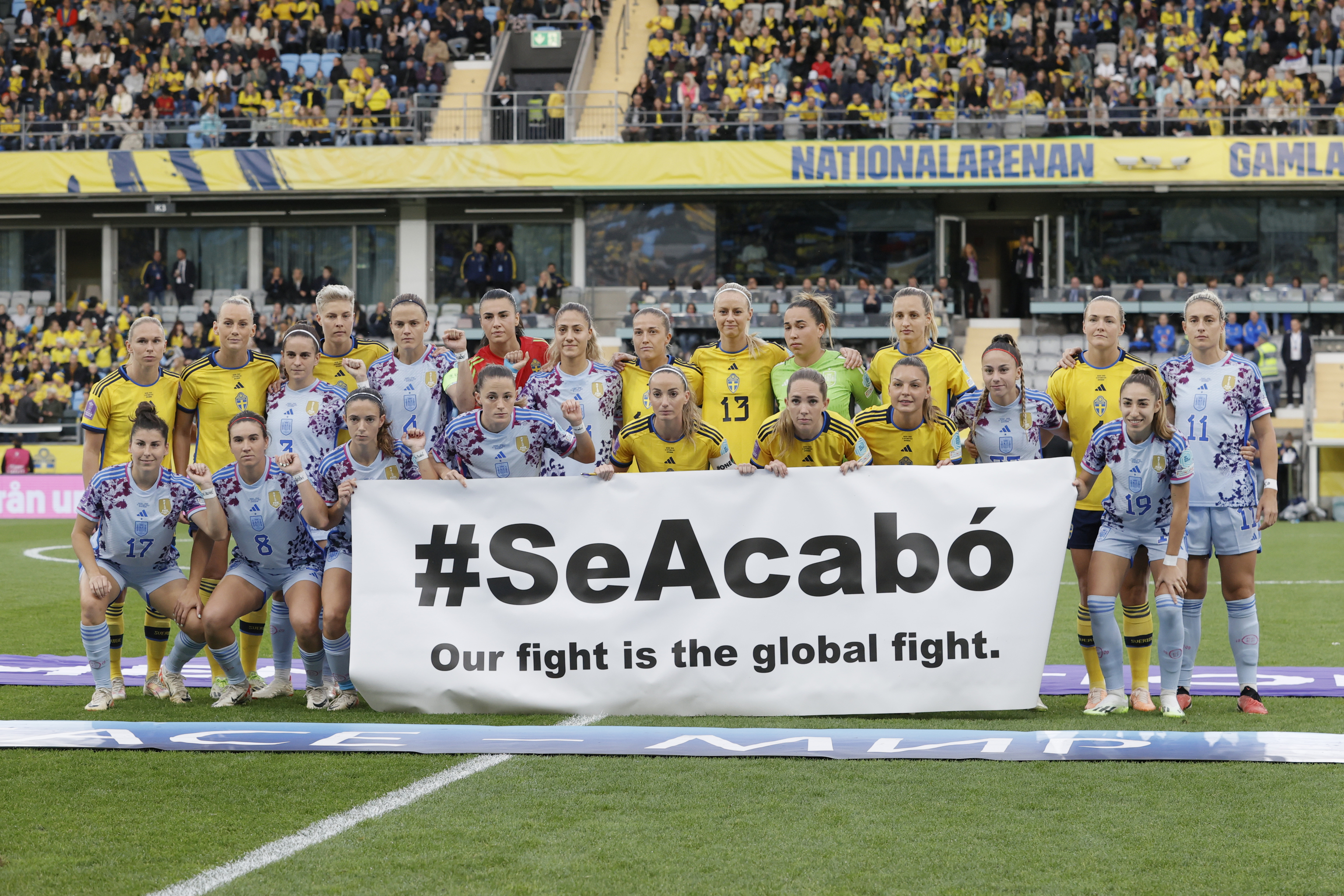 Las jugadoras de ambos equipos posan con una pancarta antes del duelo Suecia-España.