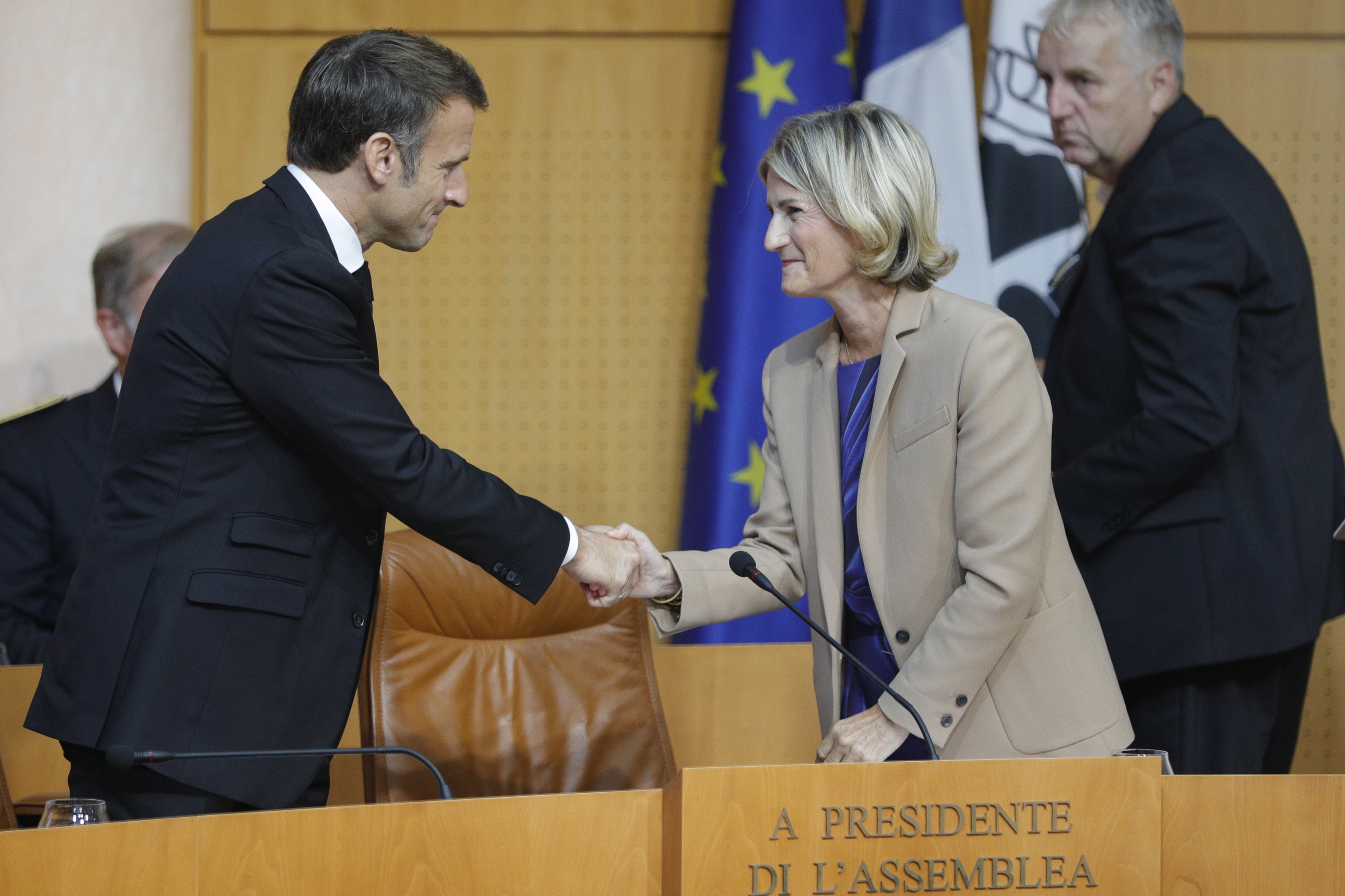 Emmanuel Macron (I) estrecha la mano de la presidenta de la Asamblea de Córcega, Marie-Antoinette Maupertuis (C).