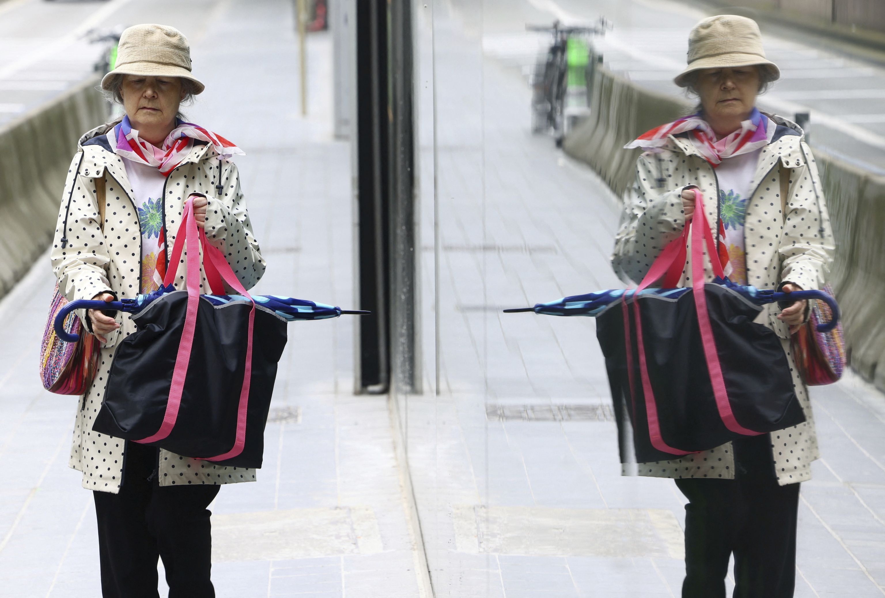 Una mujer camina en Bruselas mientras se ve reflejada en una ventana.