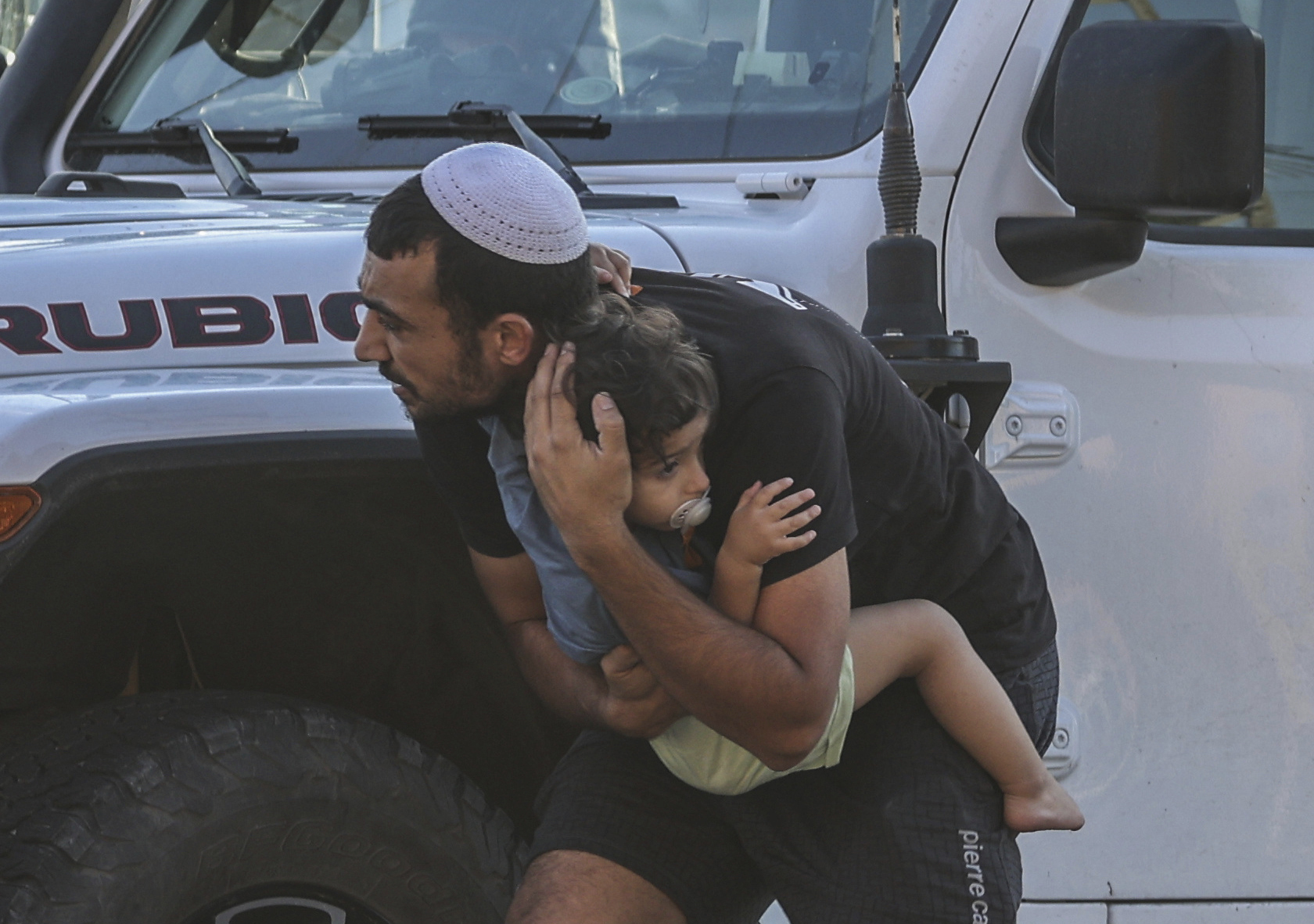 Un hombre abraza a su hijo mientras se refugia detrs de un coche en Ashkelon.