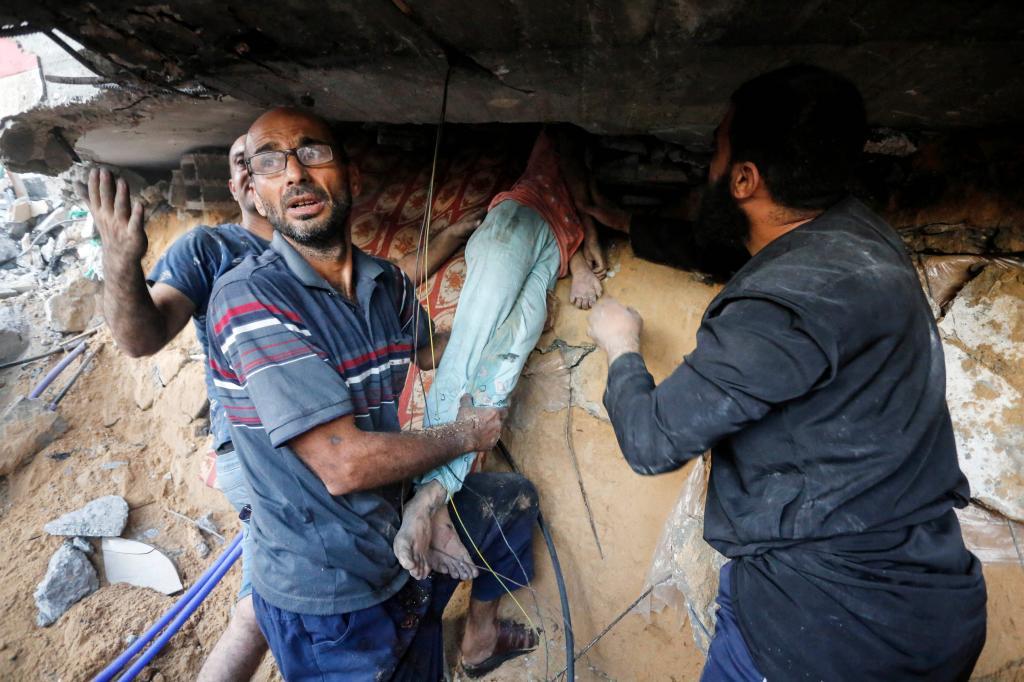 Rescatistas levantan el cuerpo de un joven de debajo de los escombros de una casa tras un ataque israel a la ciudad de Deir Al-Balah.