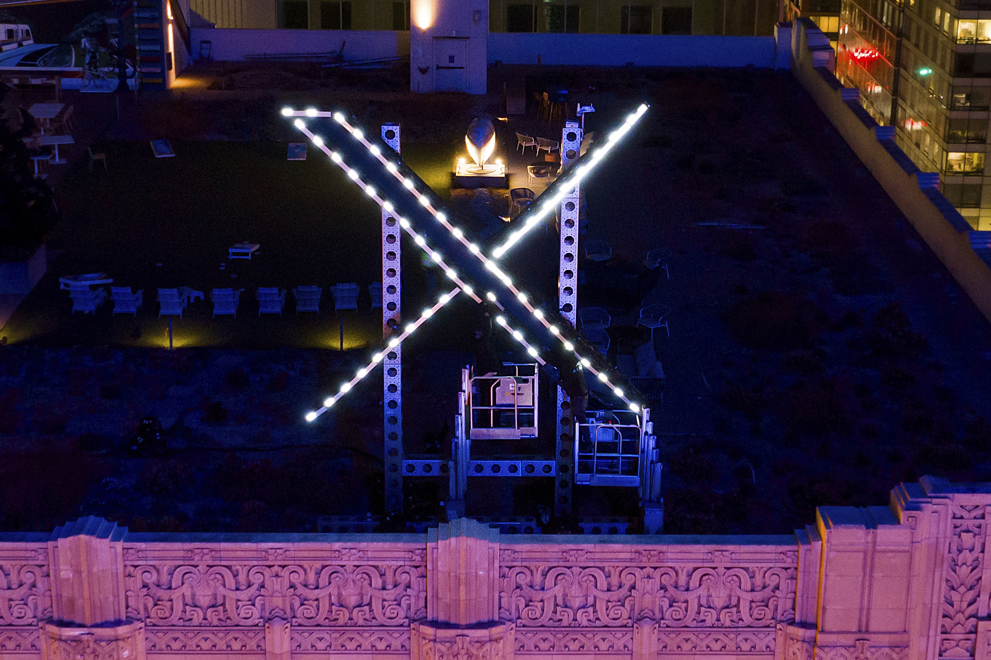Trabajadores instalan luces en un letrero de "X" encima de la sede de la compañía, anteriormente conocida como  Twitter en San Francisco (EEUU).