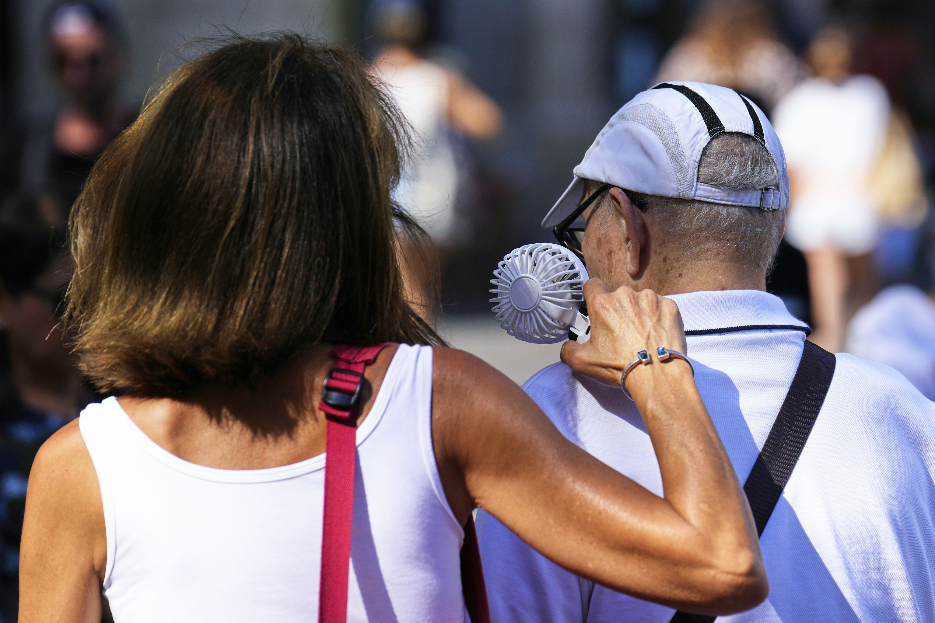 Una mujer refresca a un anciano con un ventilador en la Rambla, a finales del mes de agosto.