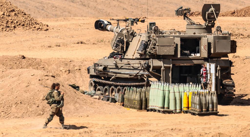 Un soldado israelí junto a un obús autopropulsado tipo M109 mientras Israel se prepara para la invasión terrestre.