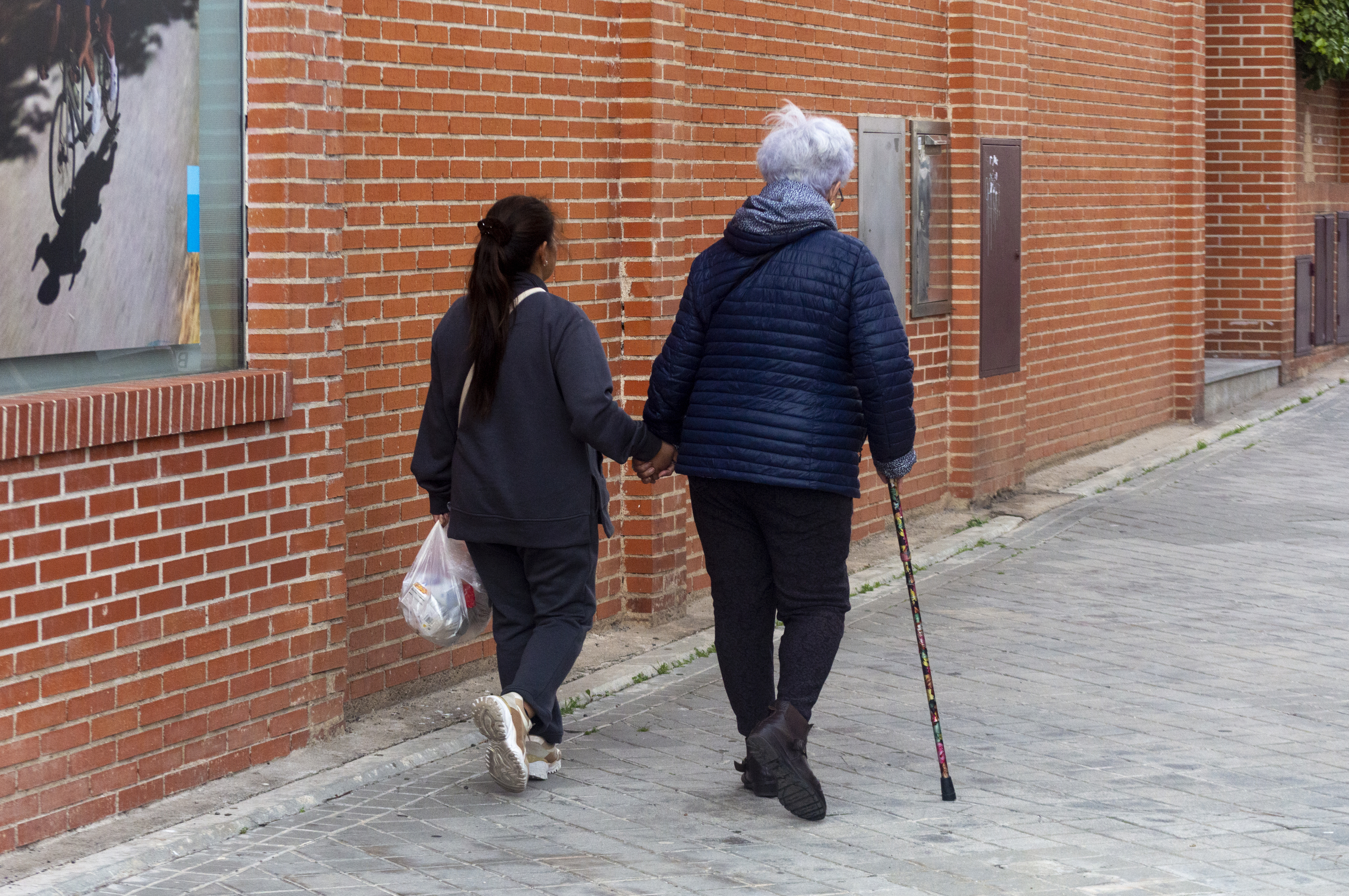 Mujer mayor acompaada de su cuidadora en las calles de Madrid.
