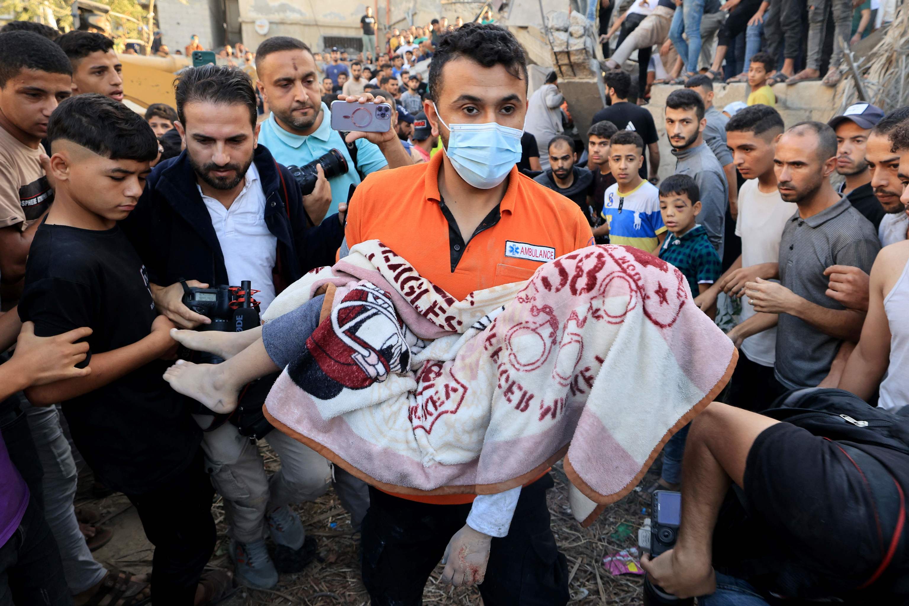 Un palestino lleva el cuerpo cubierto de un niño muerto.