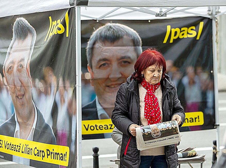 Una mujer, con un peridico con publicidad electoral y rodeada de carteles electorales, el viernes en Chisinu, Moldavia.