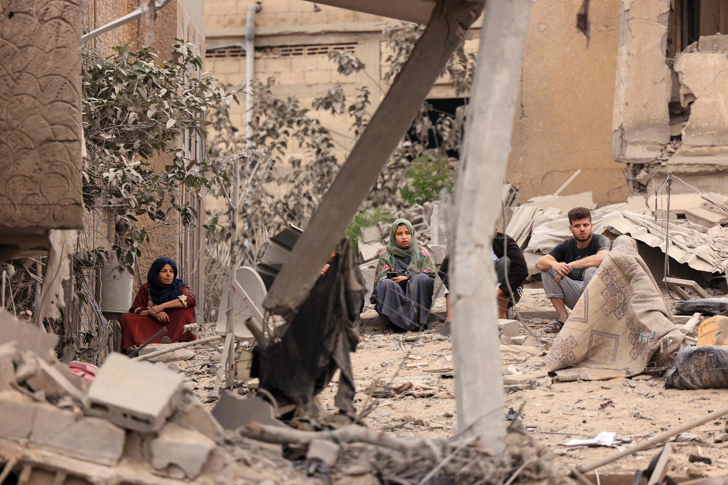 Palestinos se sientan entre las ruinas de su casa, tras un bombardeo israel