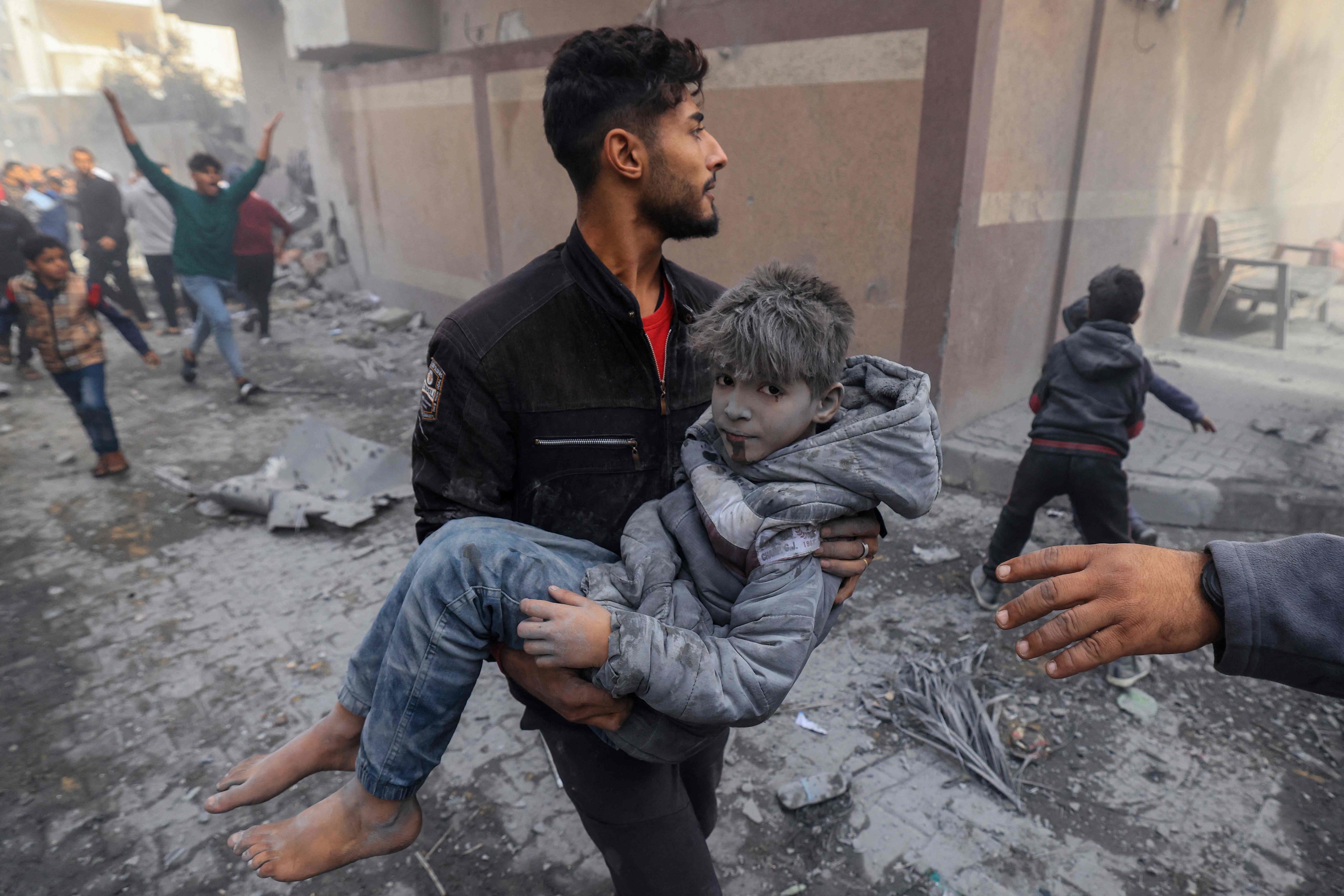 Un hombre lleva a un niño herido en un ataque israelí en Rafah.