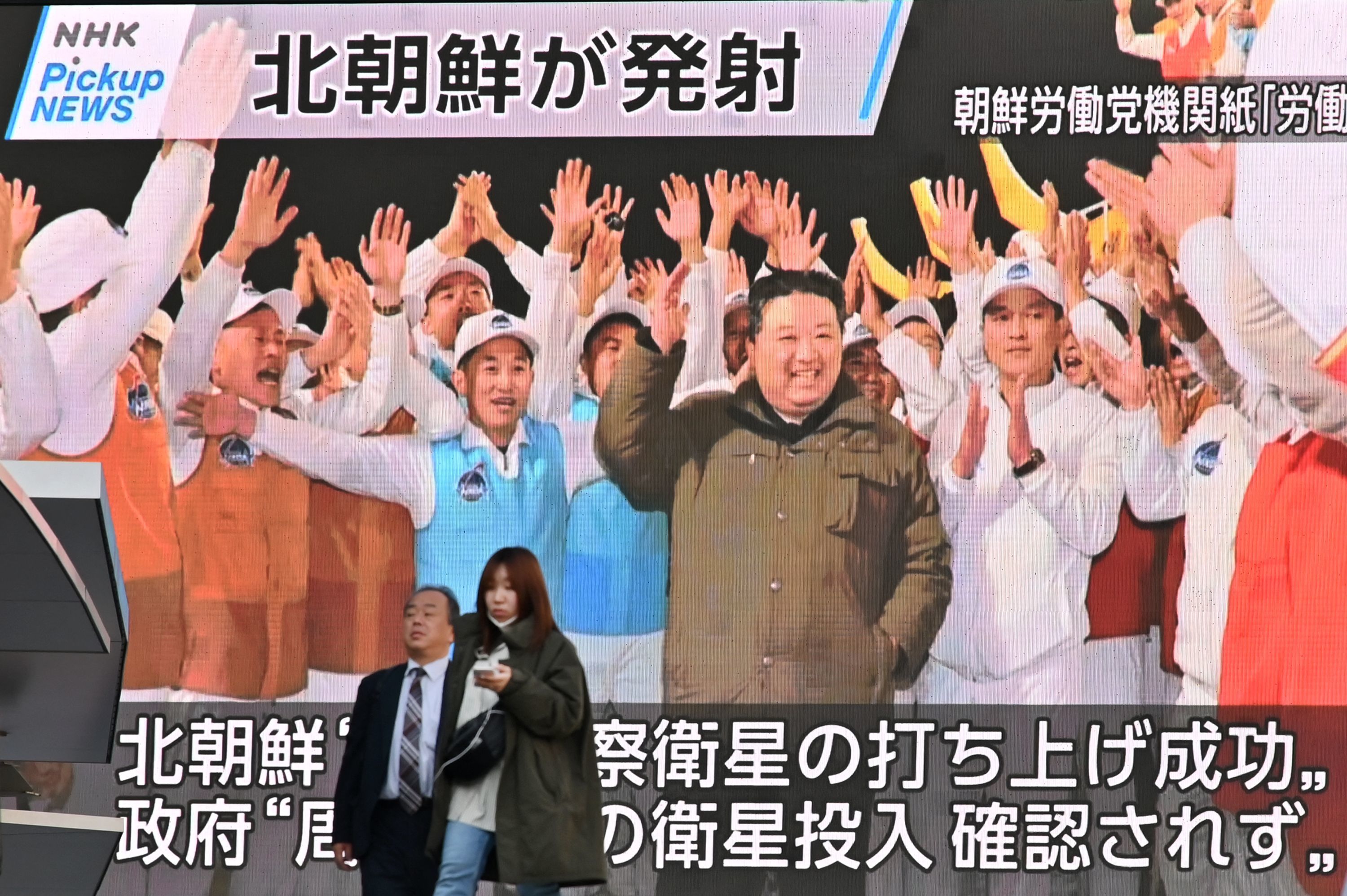 Peatones junto a una pantalla que muestra al lder de Corea del Norte celebrando el lanzamiento de su satlite espa.
