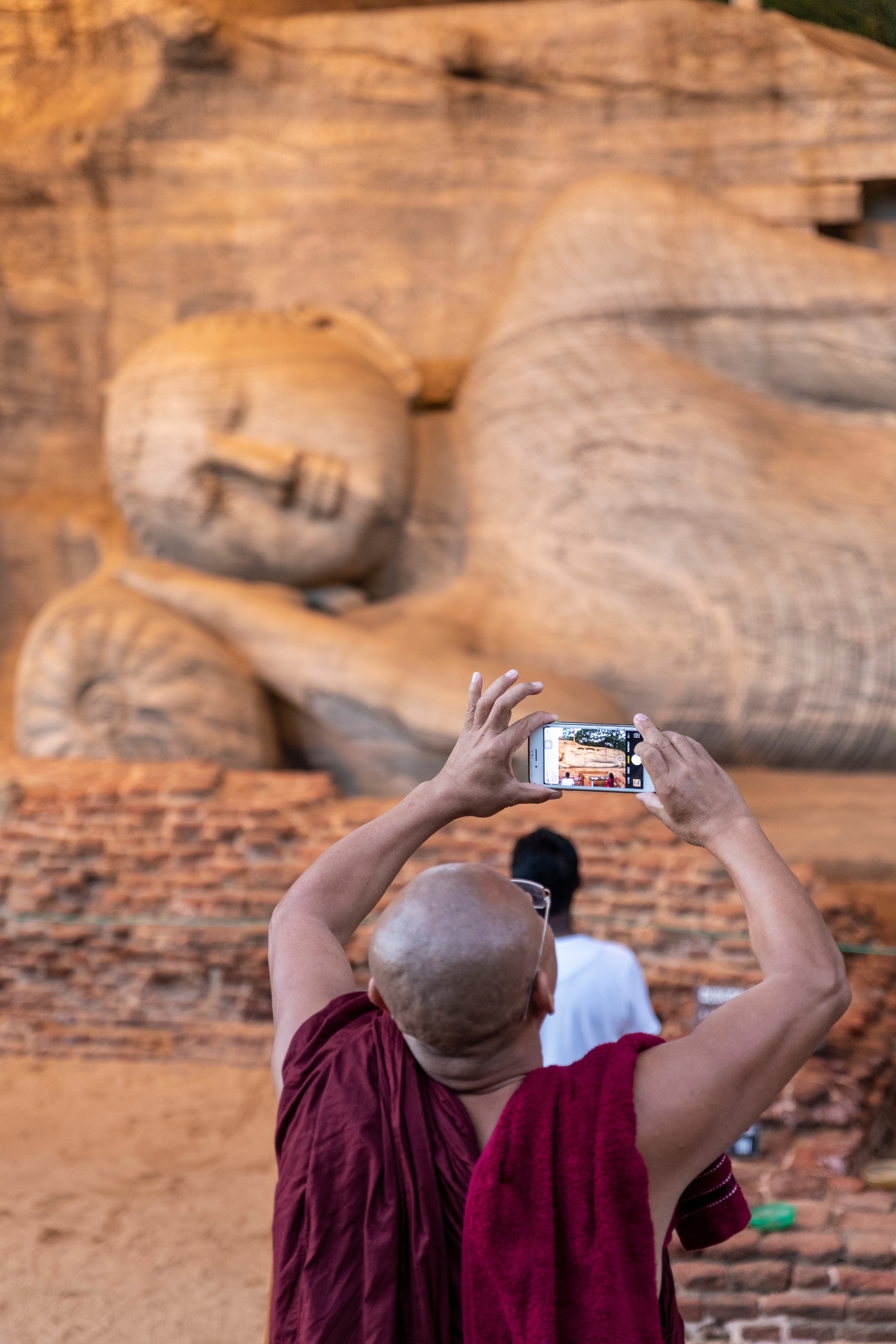 Un monje fotografía al Buda de Polonnaruwa.