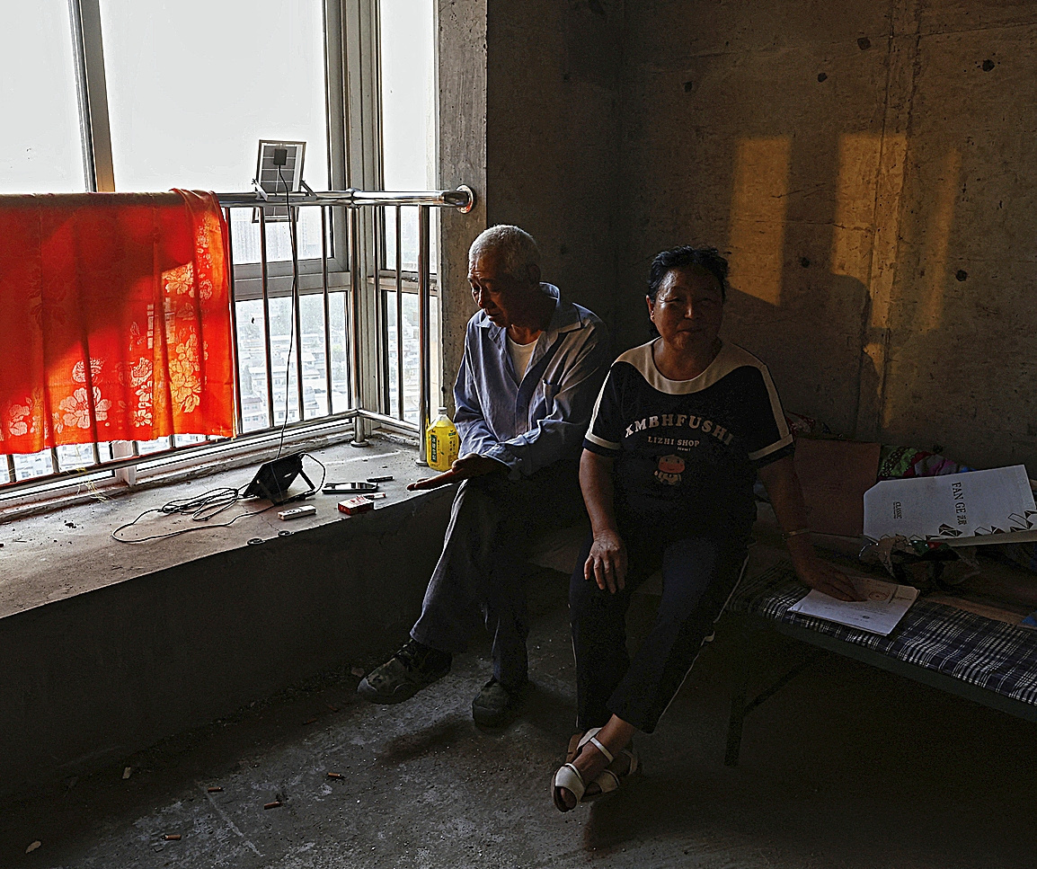 Zhao Youming y su meujer posan desde el sofá de su apartamento inacabado en la ciudad china de Tongchuan.