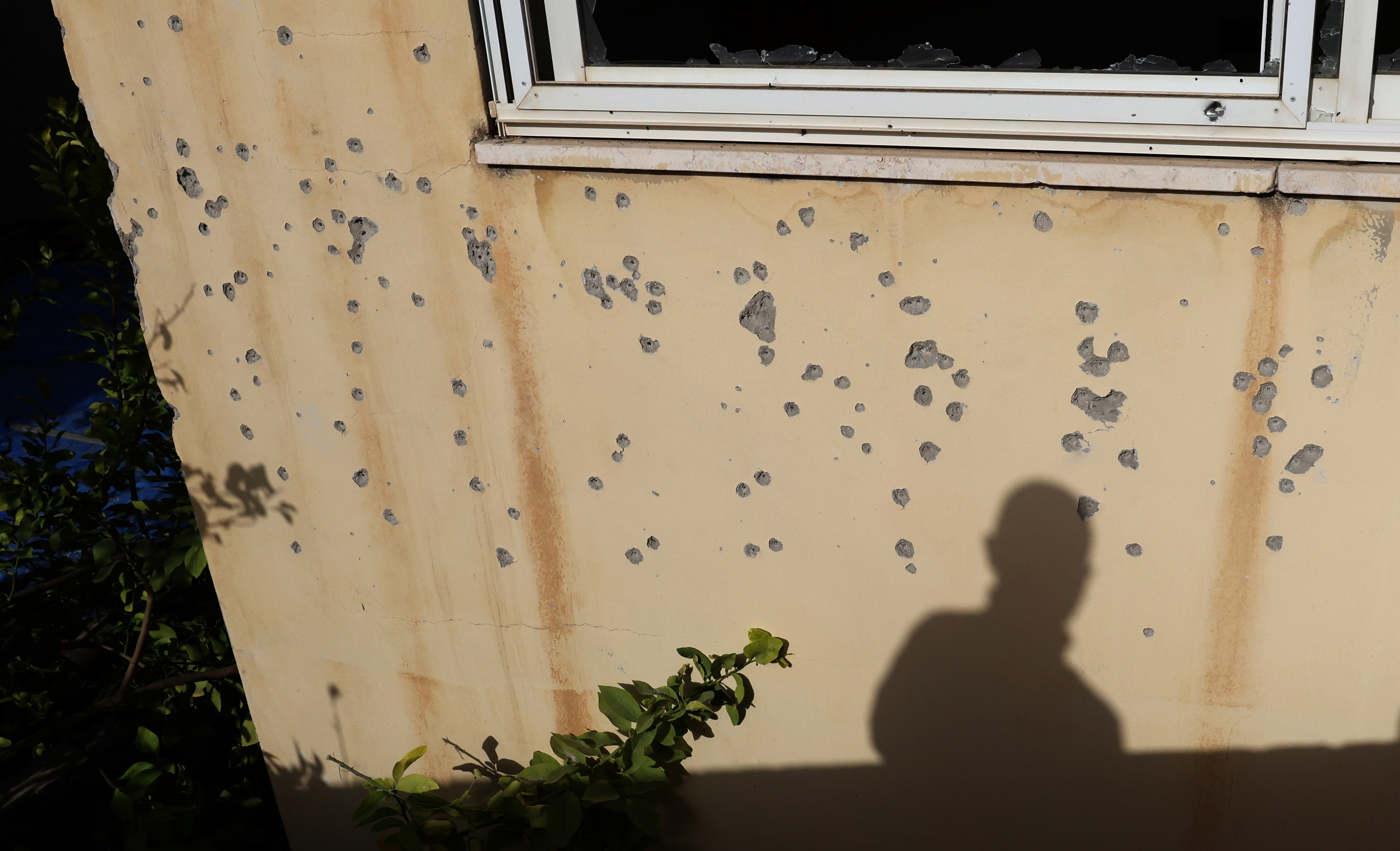 La sombra de un palestino se refleja en un muro lleno de balazos tras una incursi