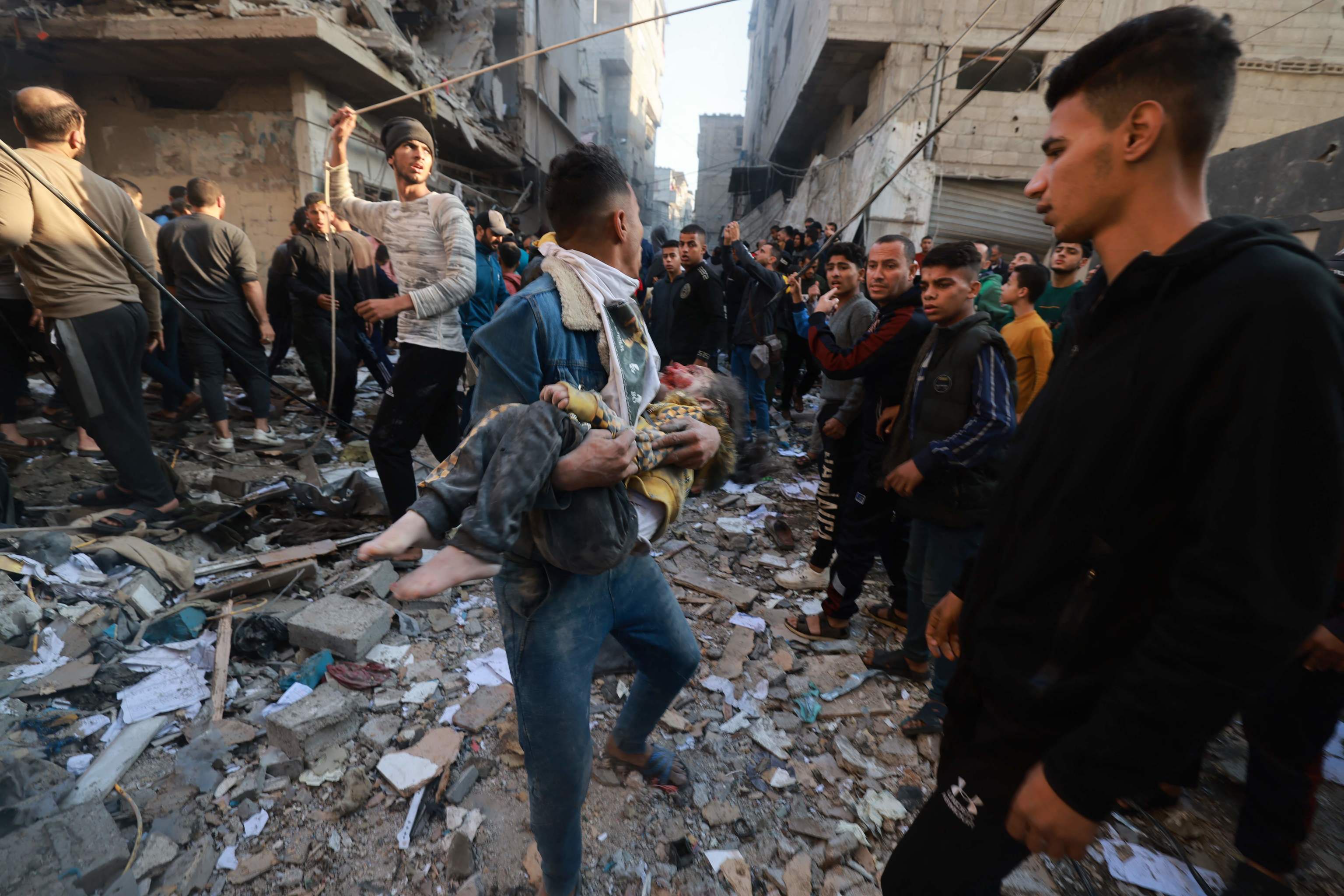 Un joven palestino lleva a un nio malherido tras un bombardeo en Rafah este viernes.
